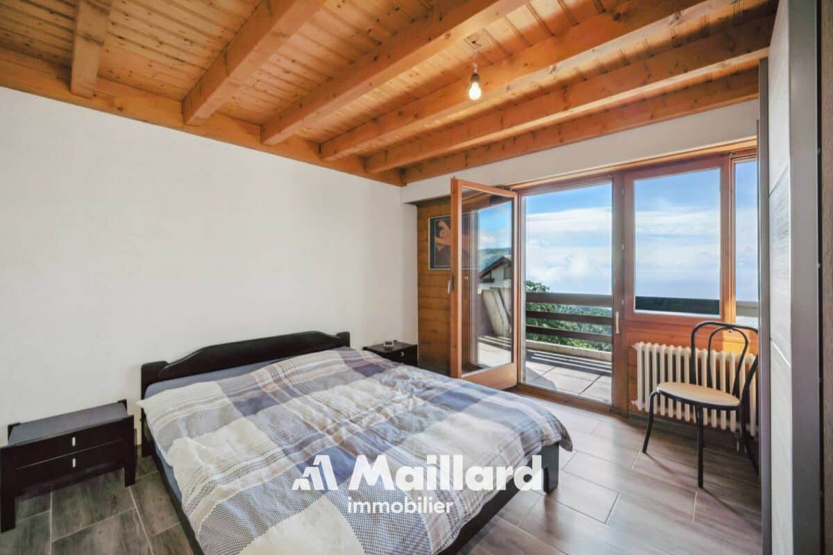 Schlafzimmer mit Holzbalkendecke und Balkonblick