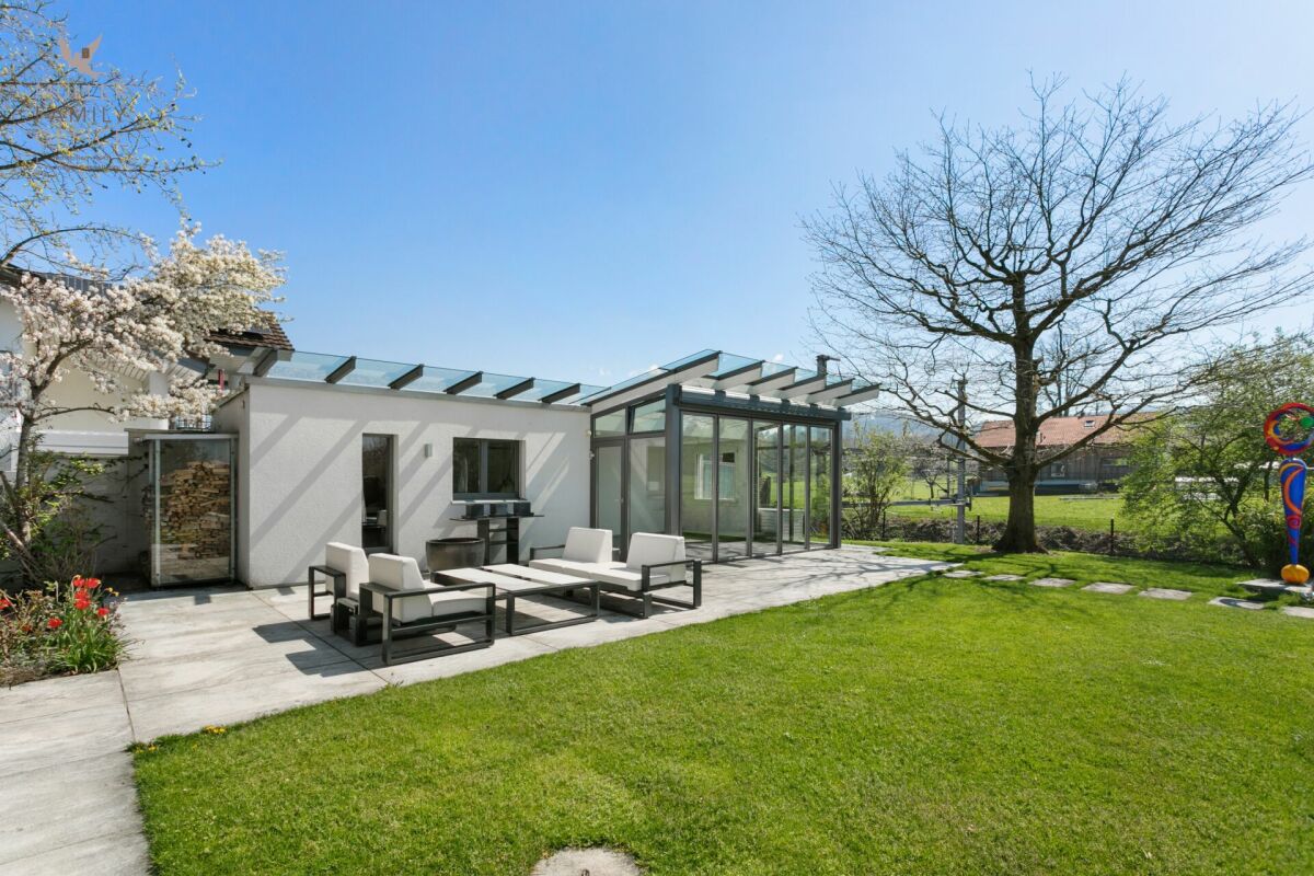 Moderner Garten mit Glasanbau und Terrasse