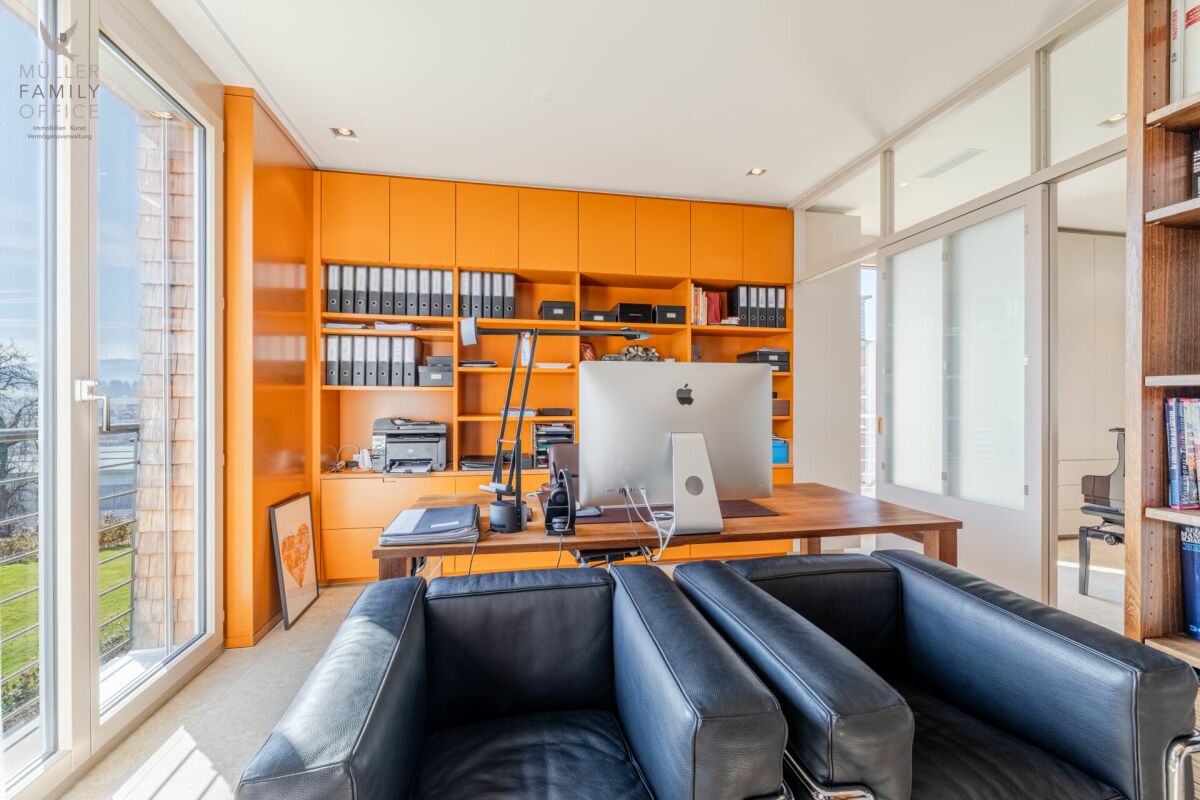Modernes Arbeitszimmer mit großem Fenster und orangefarbener Einbauschrankwand