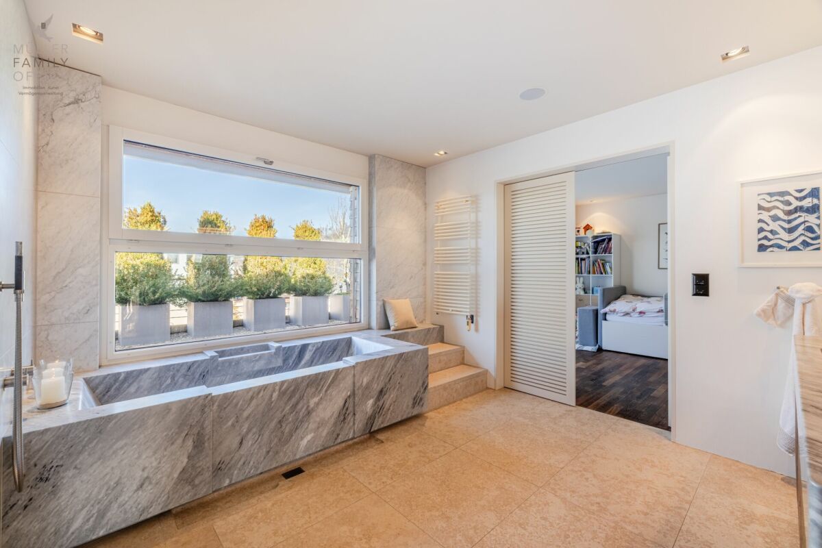 Modernes Badezimmer mit Natursteinbadewanne und großem Fenster