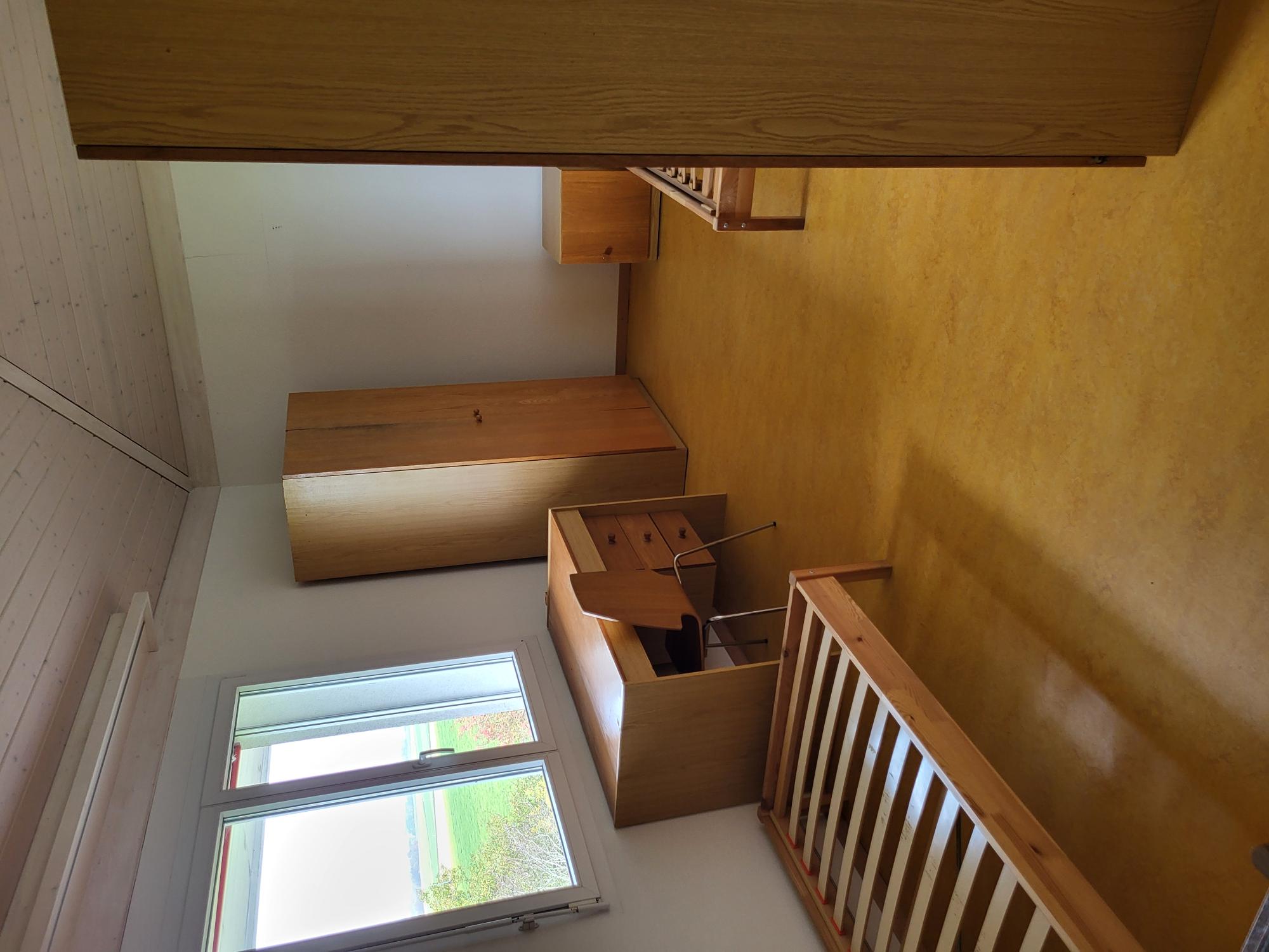 Ein schlichtes Schlafzimmer mit Holzmöbeln und Blick ins Grüne