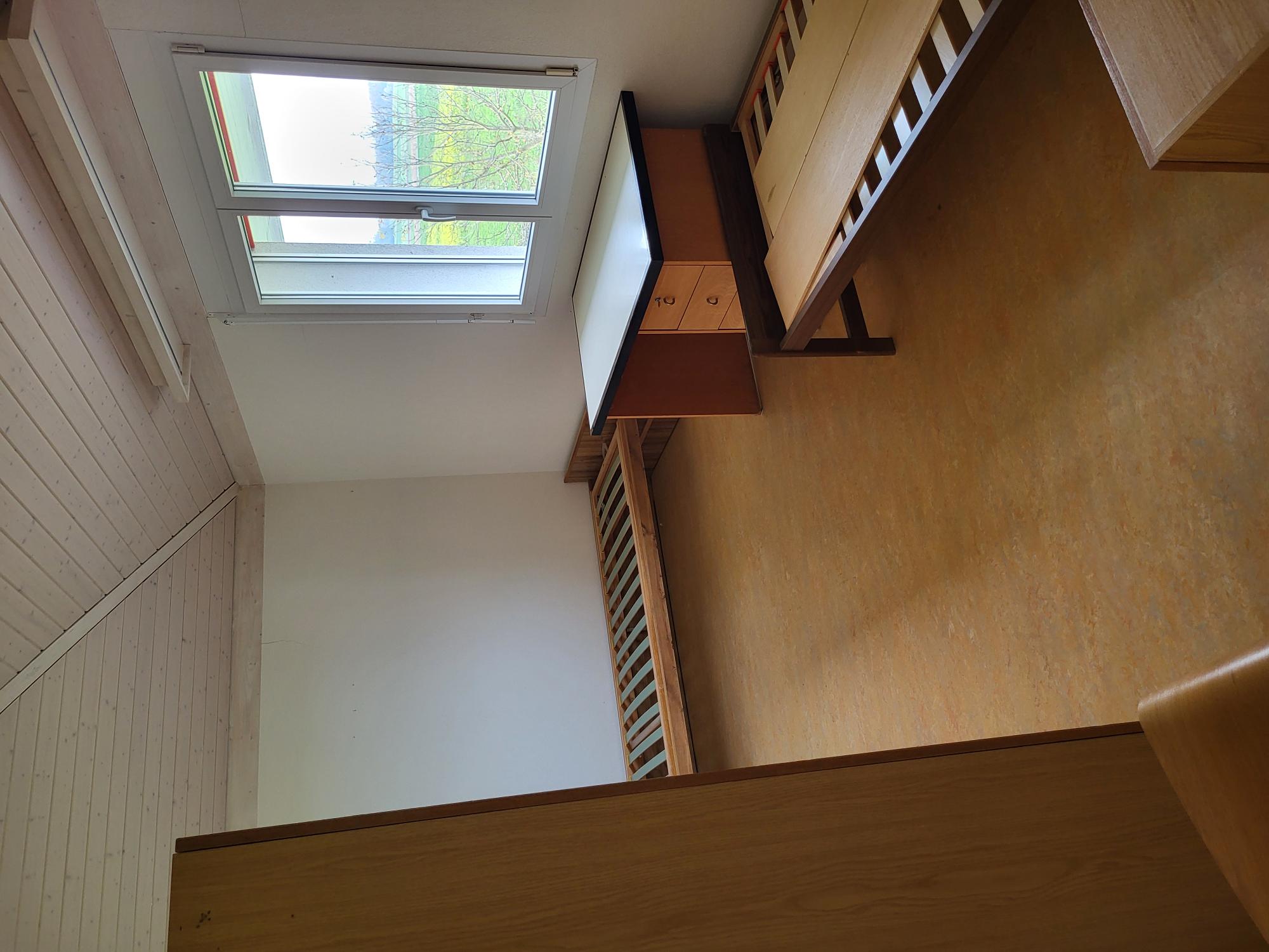 Ein schlichtes Schlafzimmer im Dachgeschoss mit zwei Einzelbetten und Fensterblick.