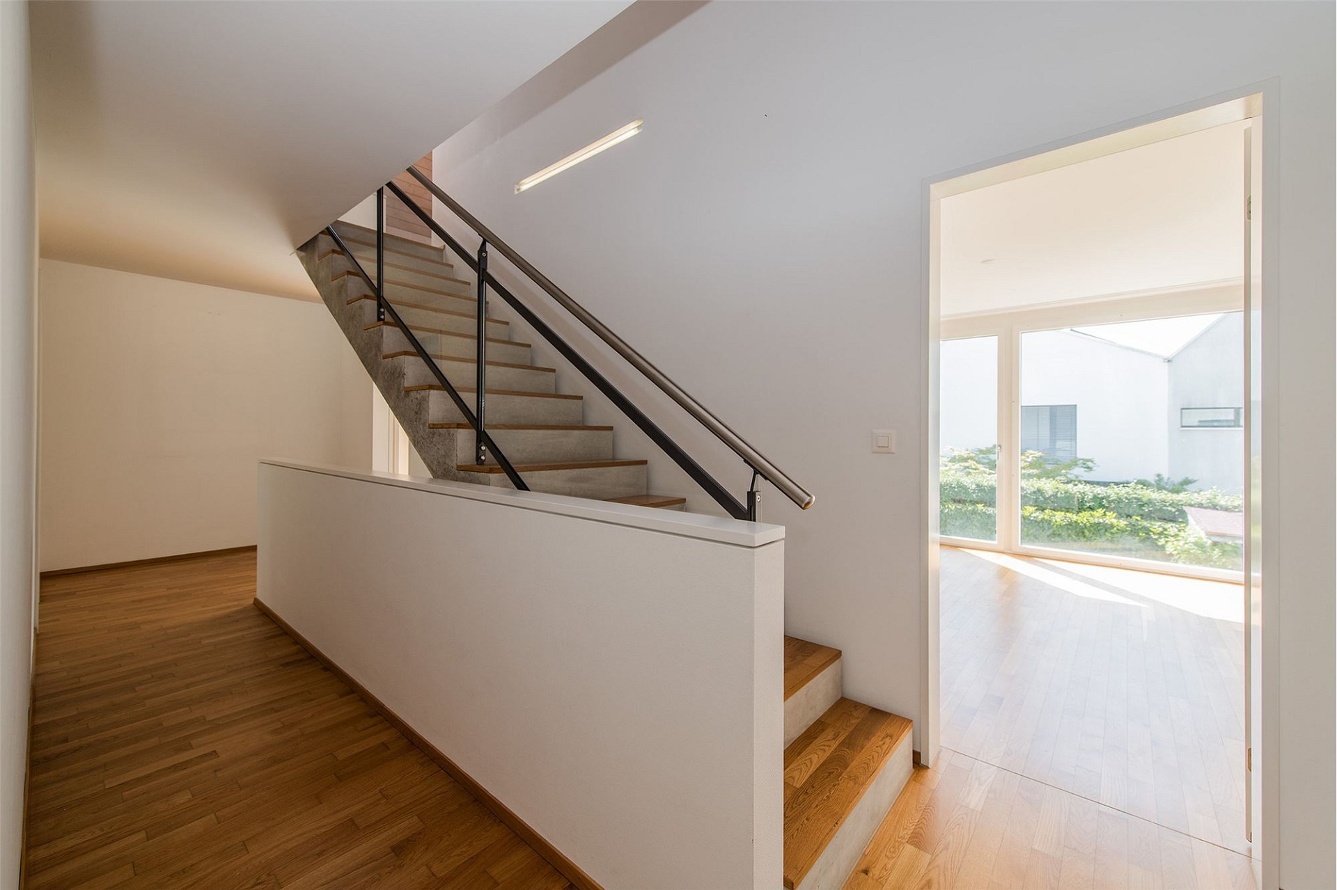 Heller Flur mit Treppe und Blick in einen Nebenraum