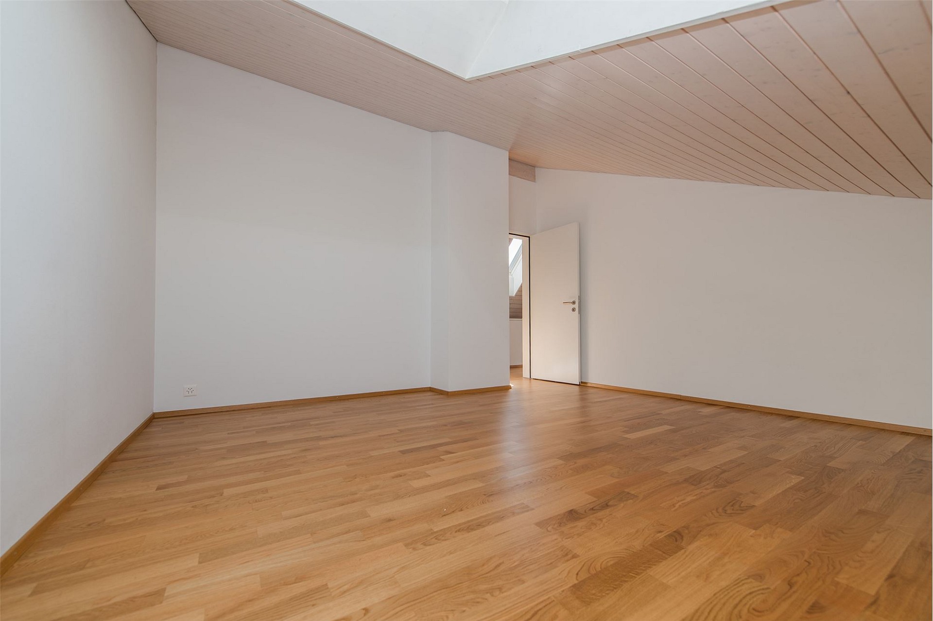 Heller leerer Raum mit Holzdecke und Parkett