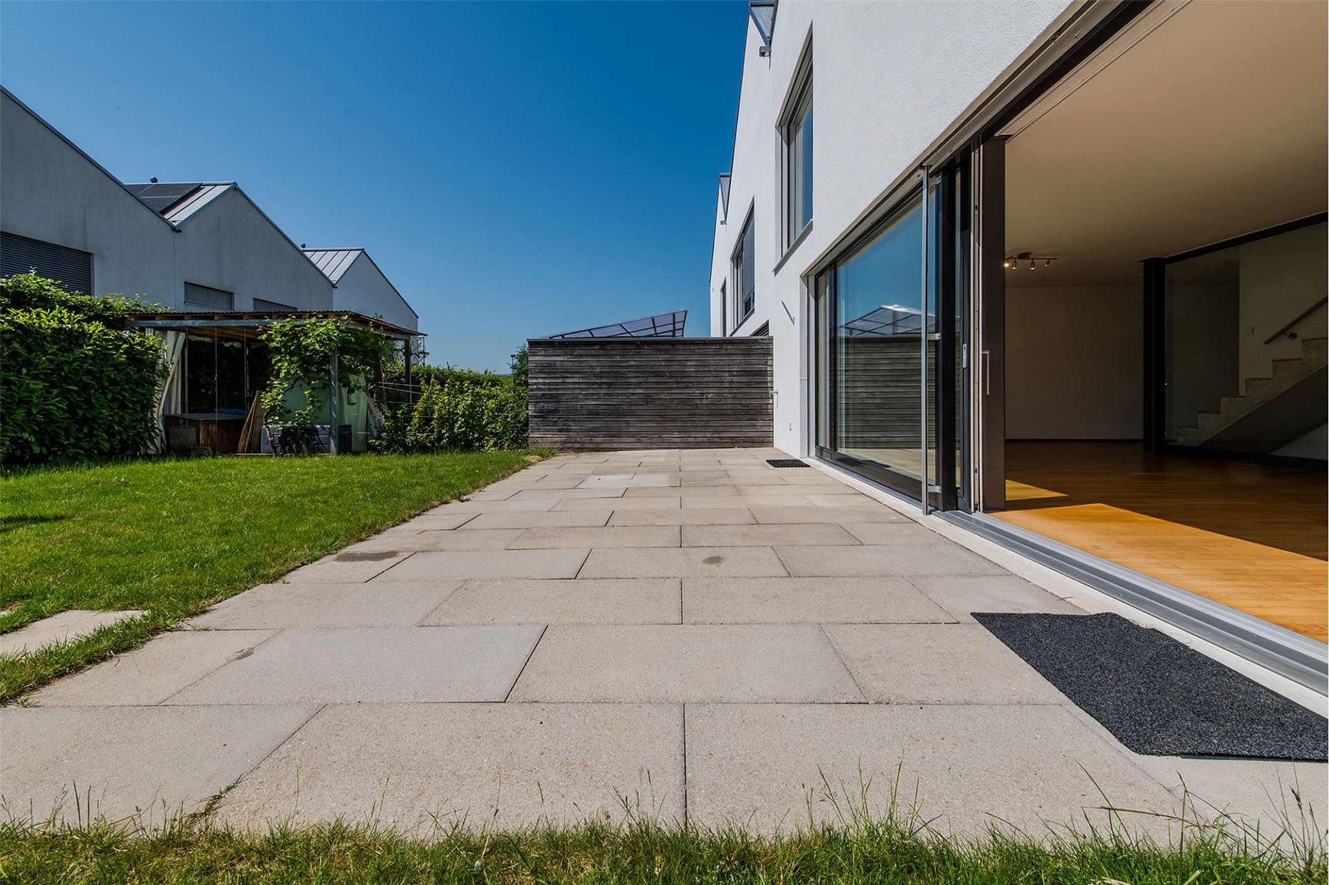Moderner Garten mit Terrasse und bodentiefen Schiebetüren