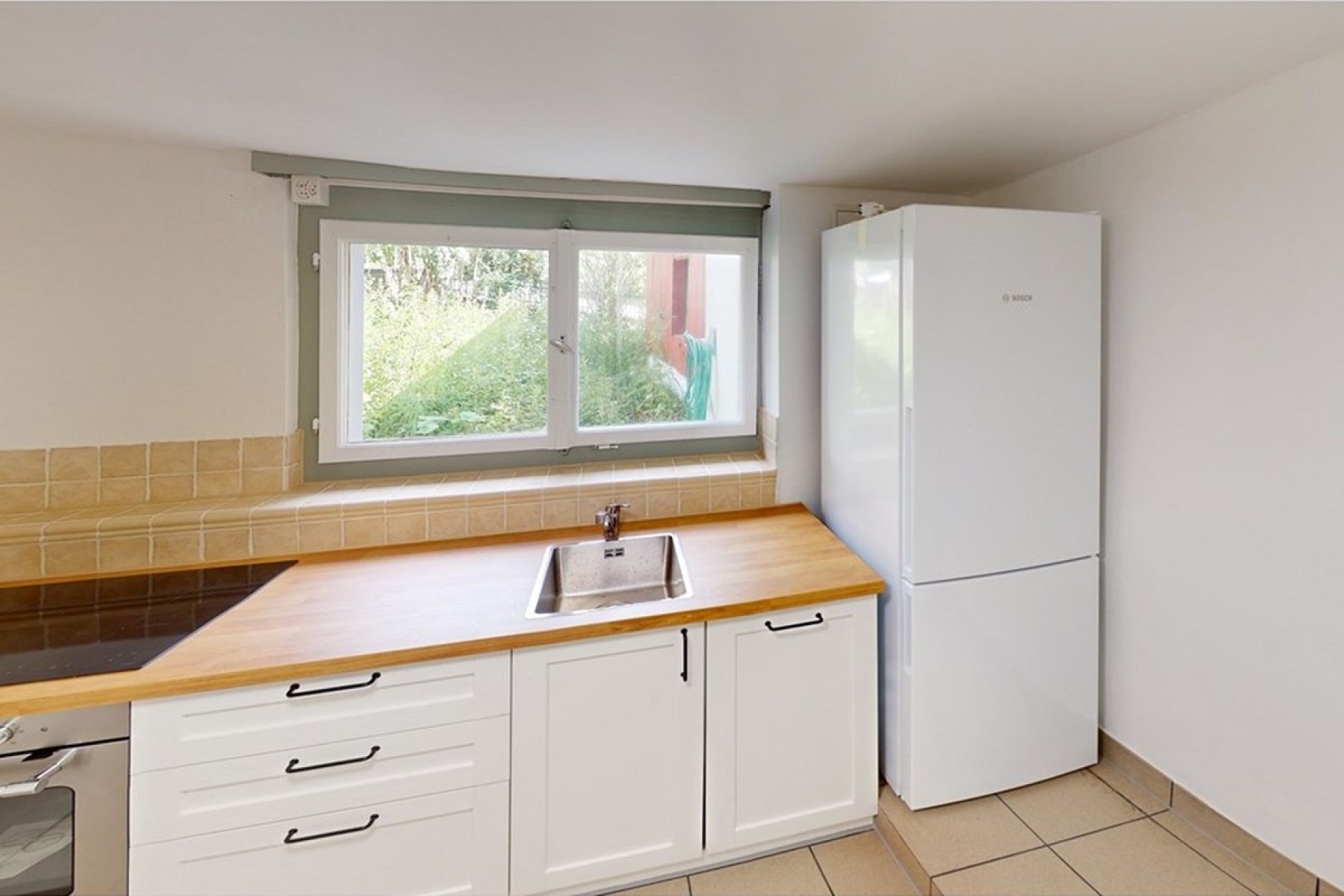 Helle Küche mit Fenster und weißem Kühlschrank