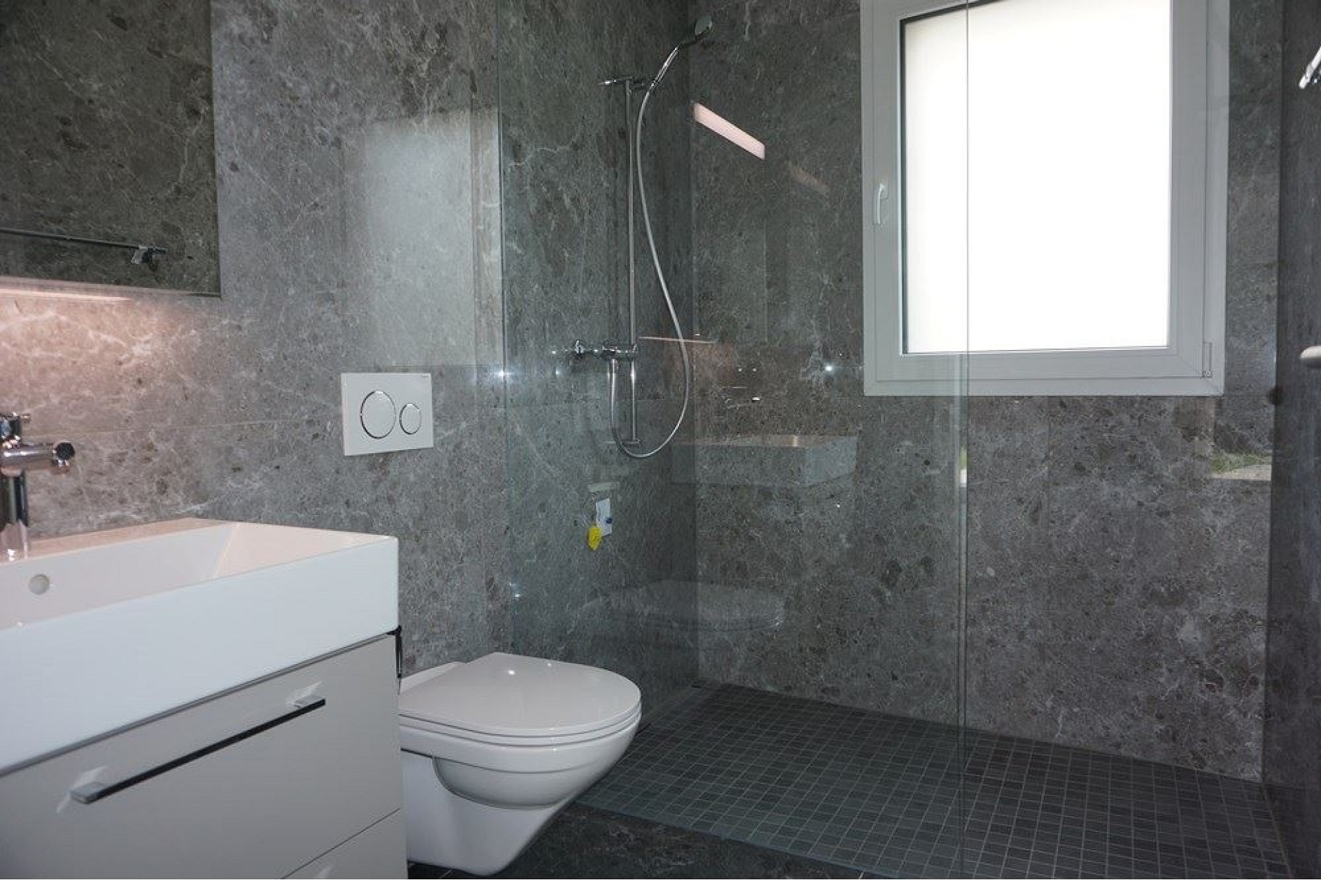 Modernes Badezimmer mit bodengleicher Dusche und grauen Steinoberflächen