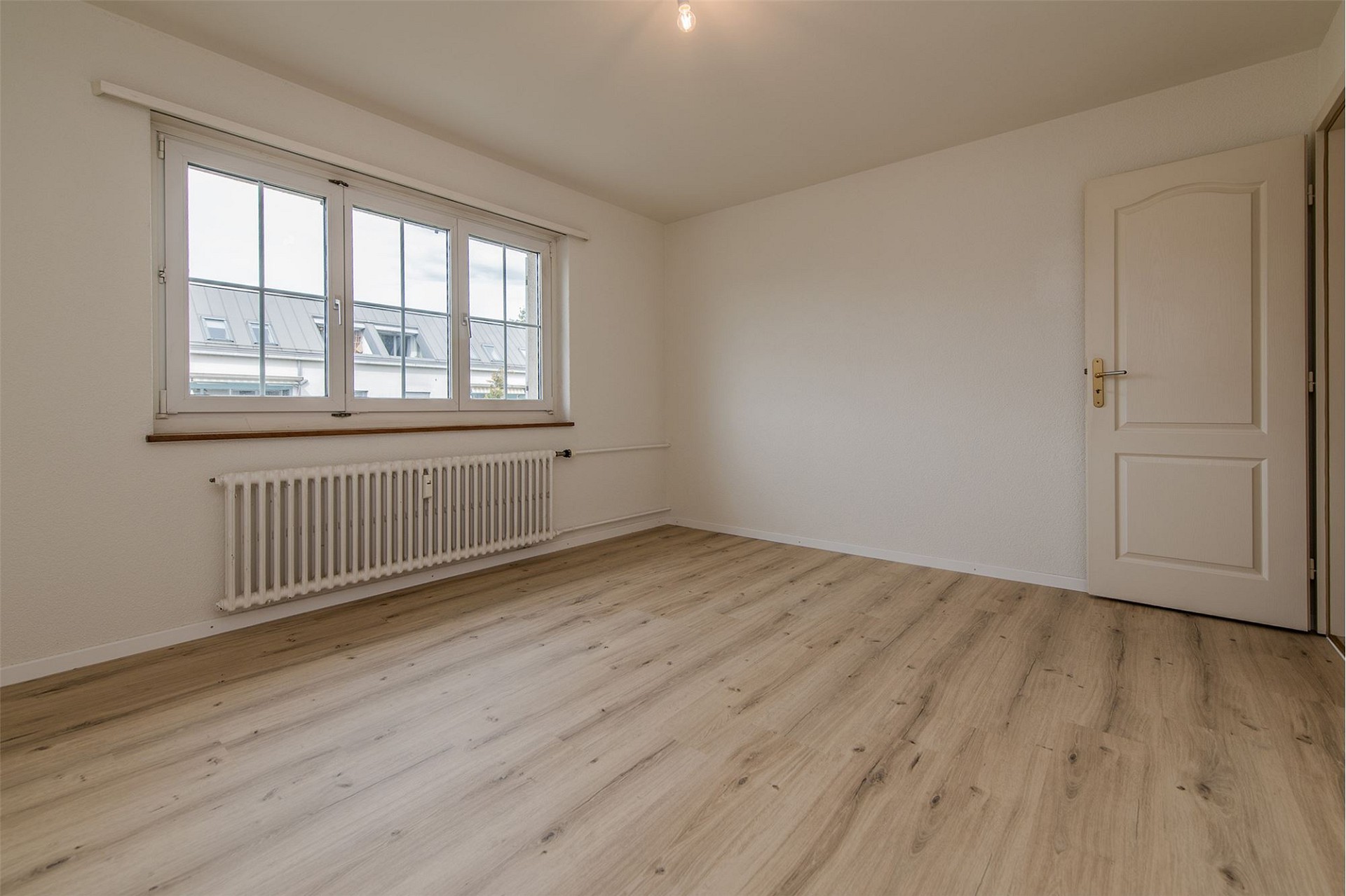 Helles, leeres Zimmer mit Fenster und Heizkörper