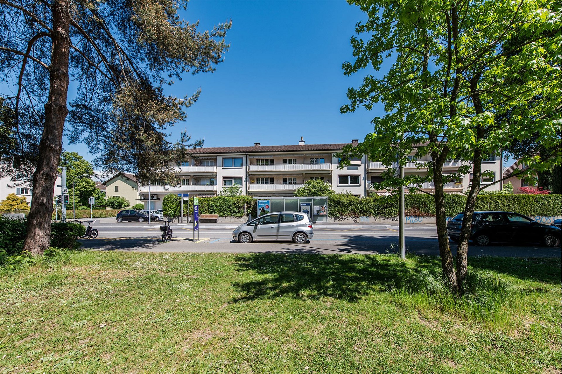 Wohnhaus an einer Straße mit Grünfläche im Vordergrund