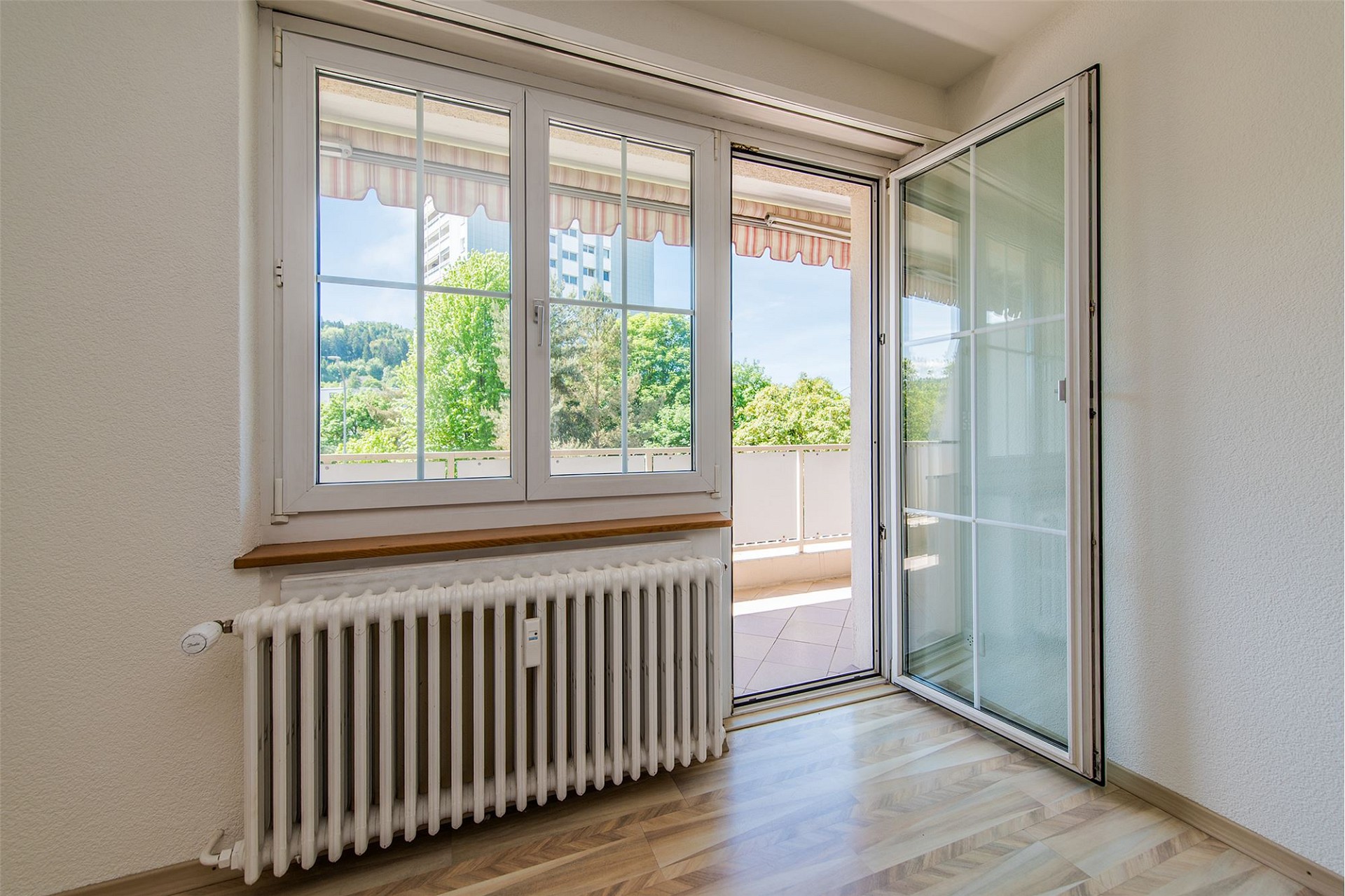 Heller Raum mit geöffnetem Fenster zum Balkon
