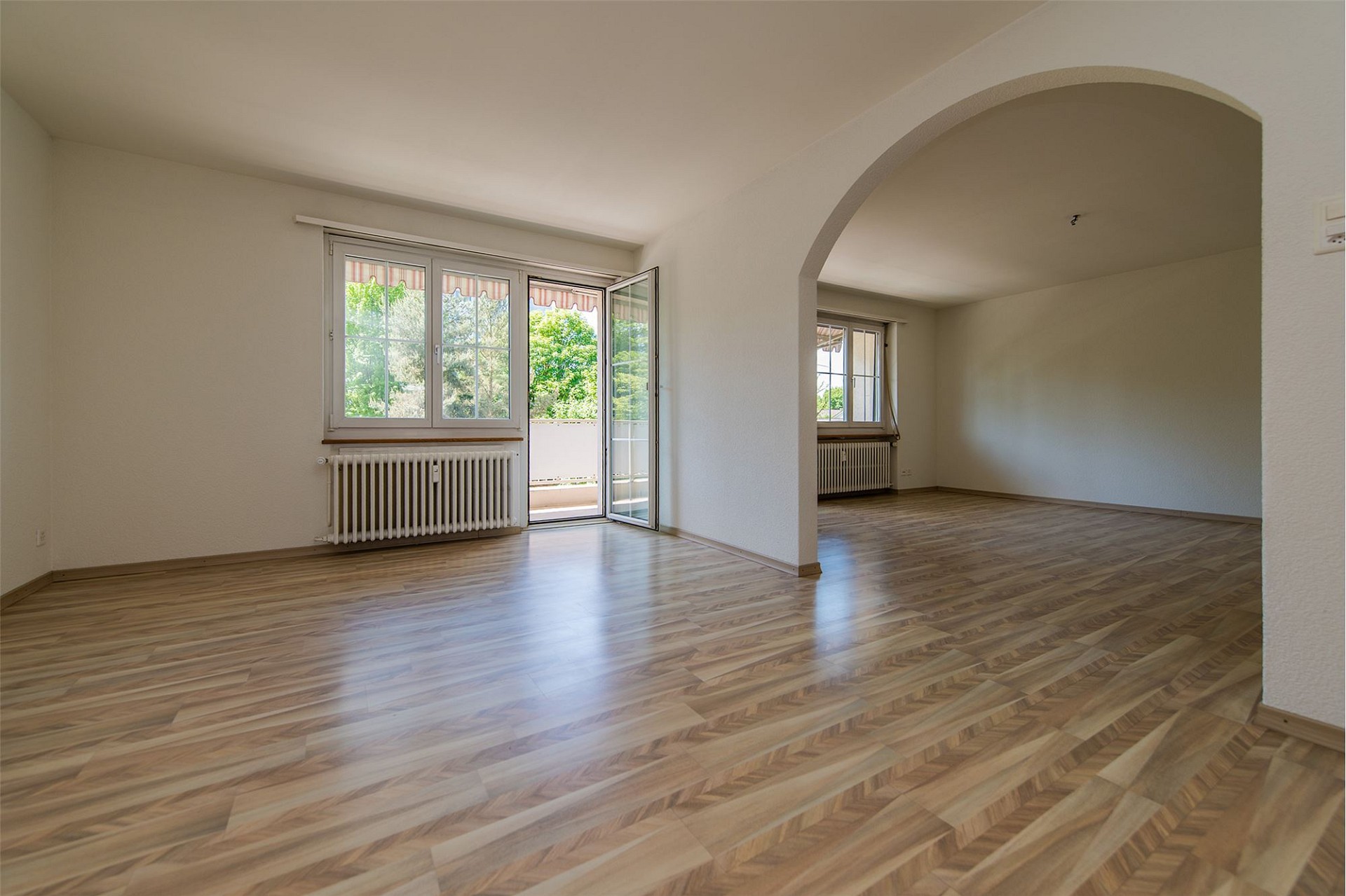 Heller leerer Wohnraum mit Balkon und Rundbogenöffnung