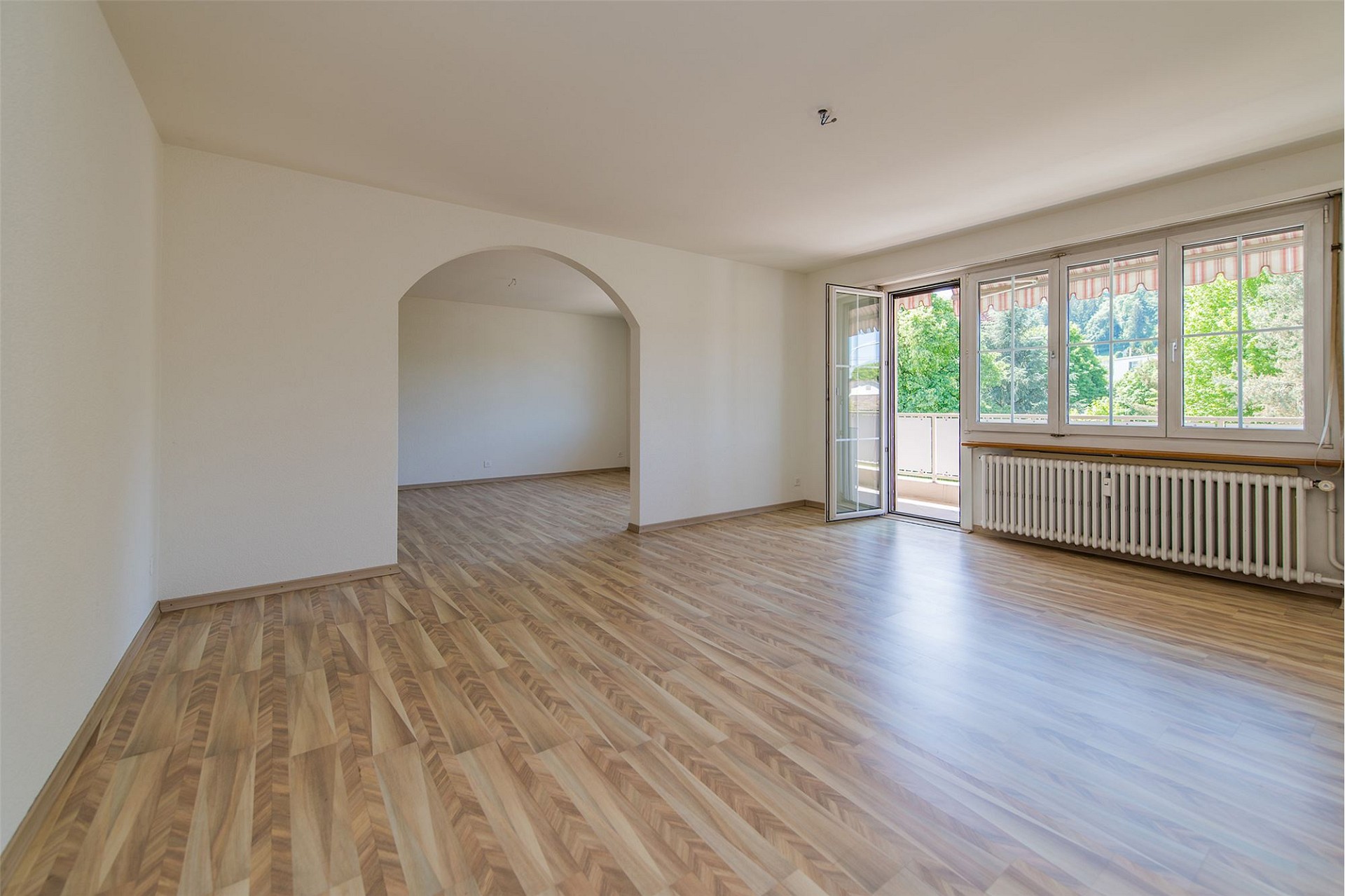 Heller leerer Wohnraum mit Balkon und Bogenöffnung