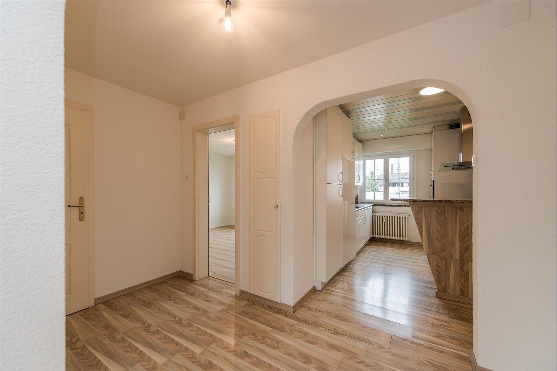 Heller Wohnungsflur mit Durchgang zur Küche