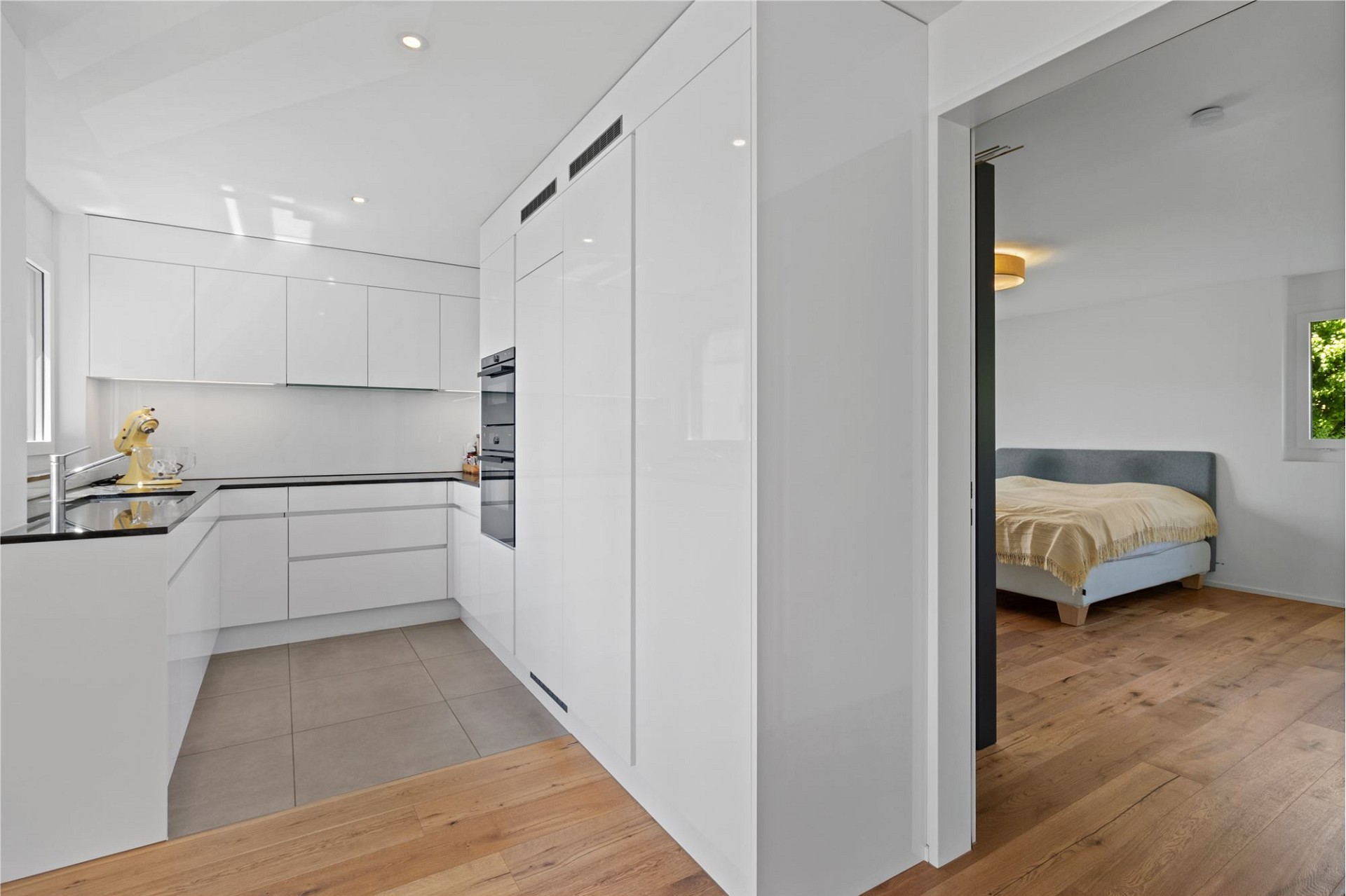 Moderne weiße Küche mit angrenzendem Schlafzimmer
