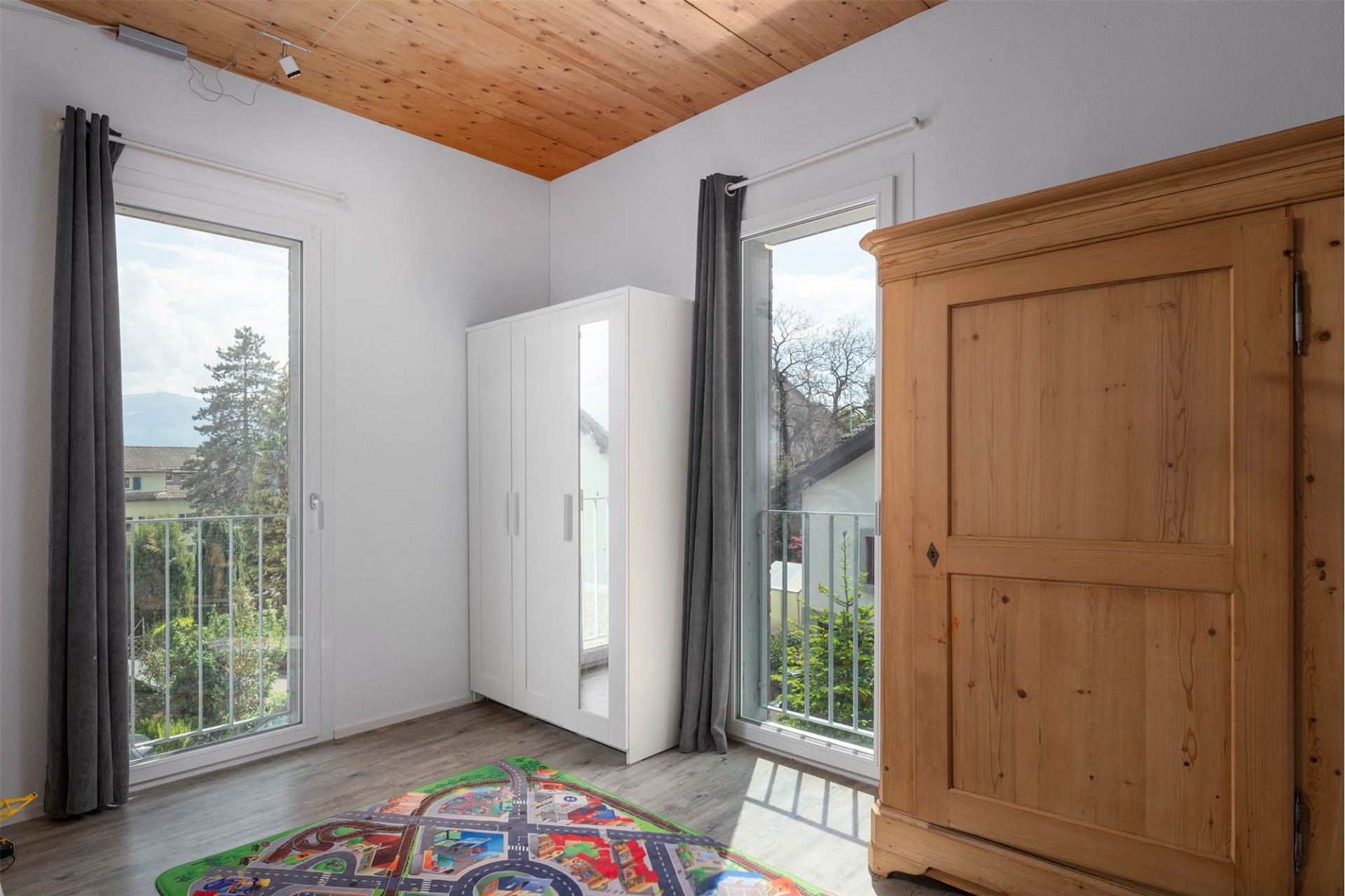 Helles Zimmer mit hohen Fenstern und Holzdecke