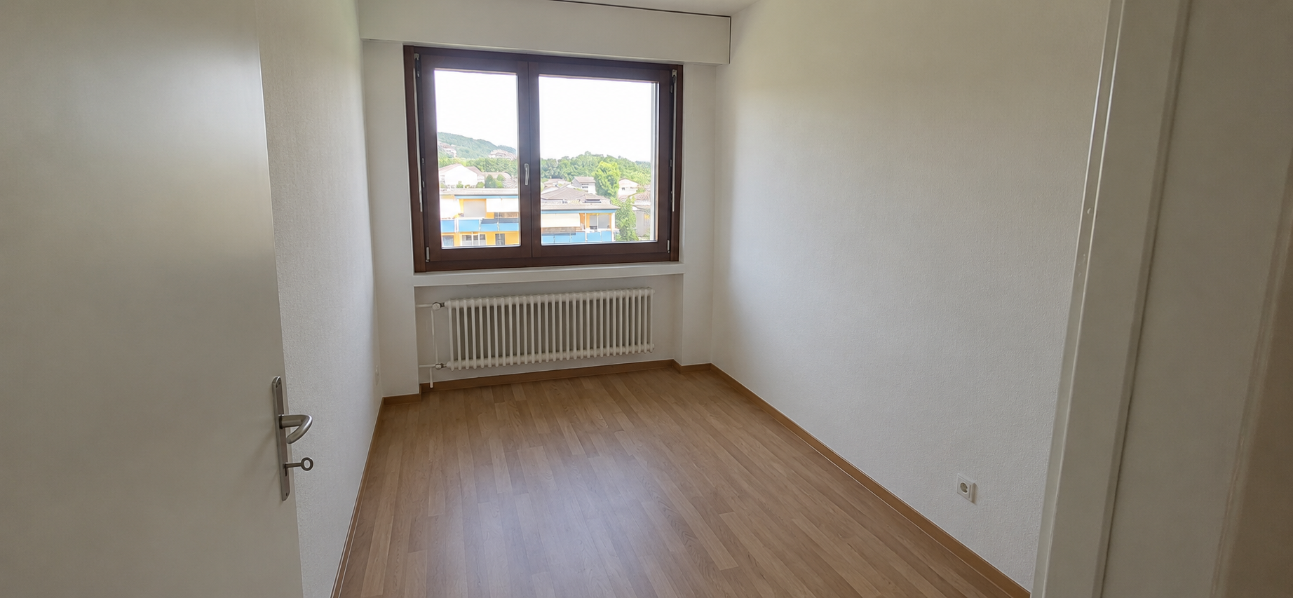 Helles, leeres Zimmer mit Fenster und Heizkörper