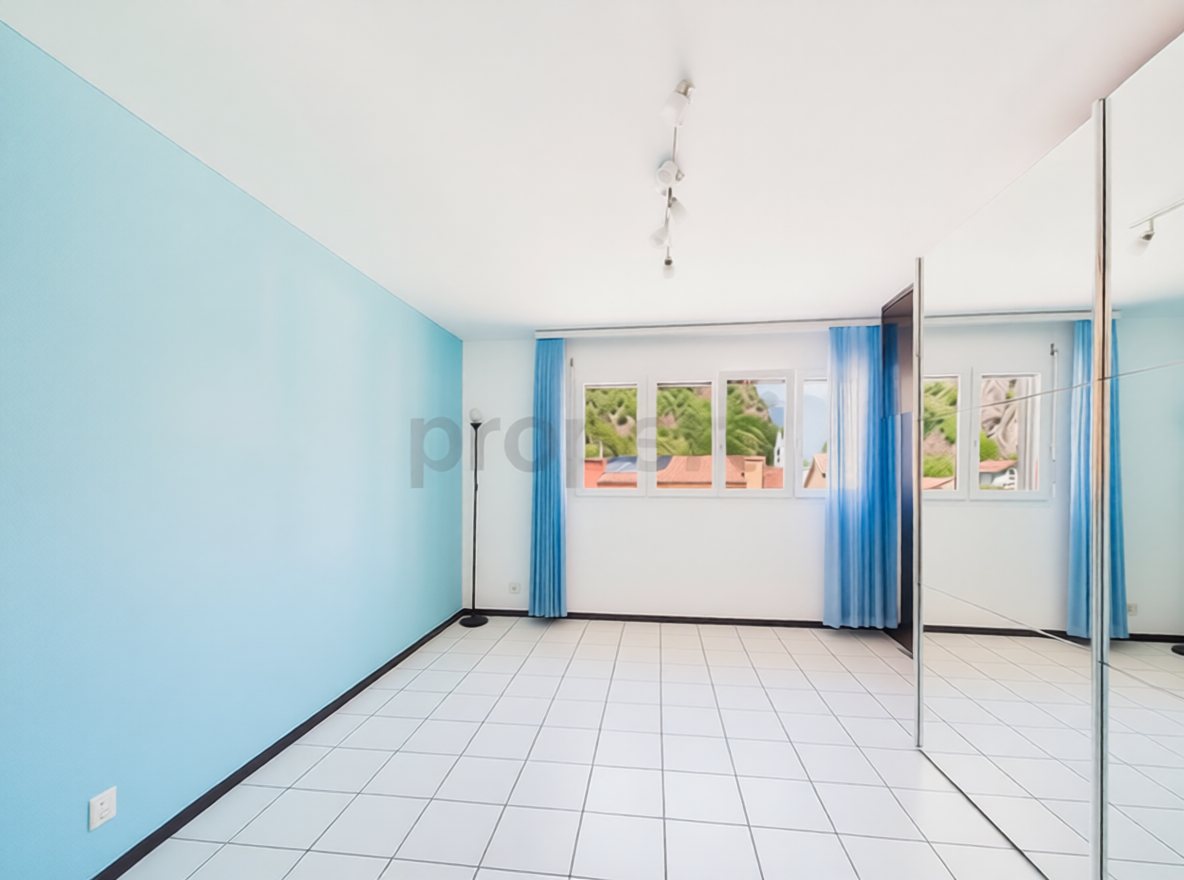 Helles, leeres Zimmer mit Fliesenboden und großen Fenstern