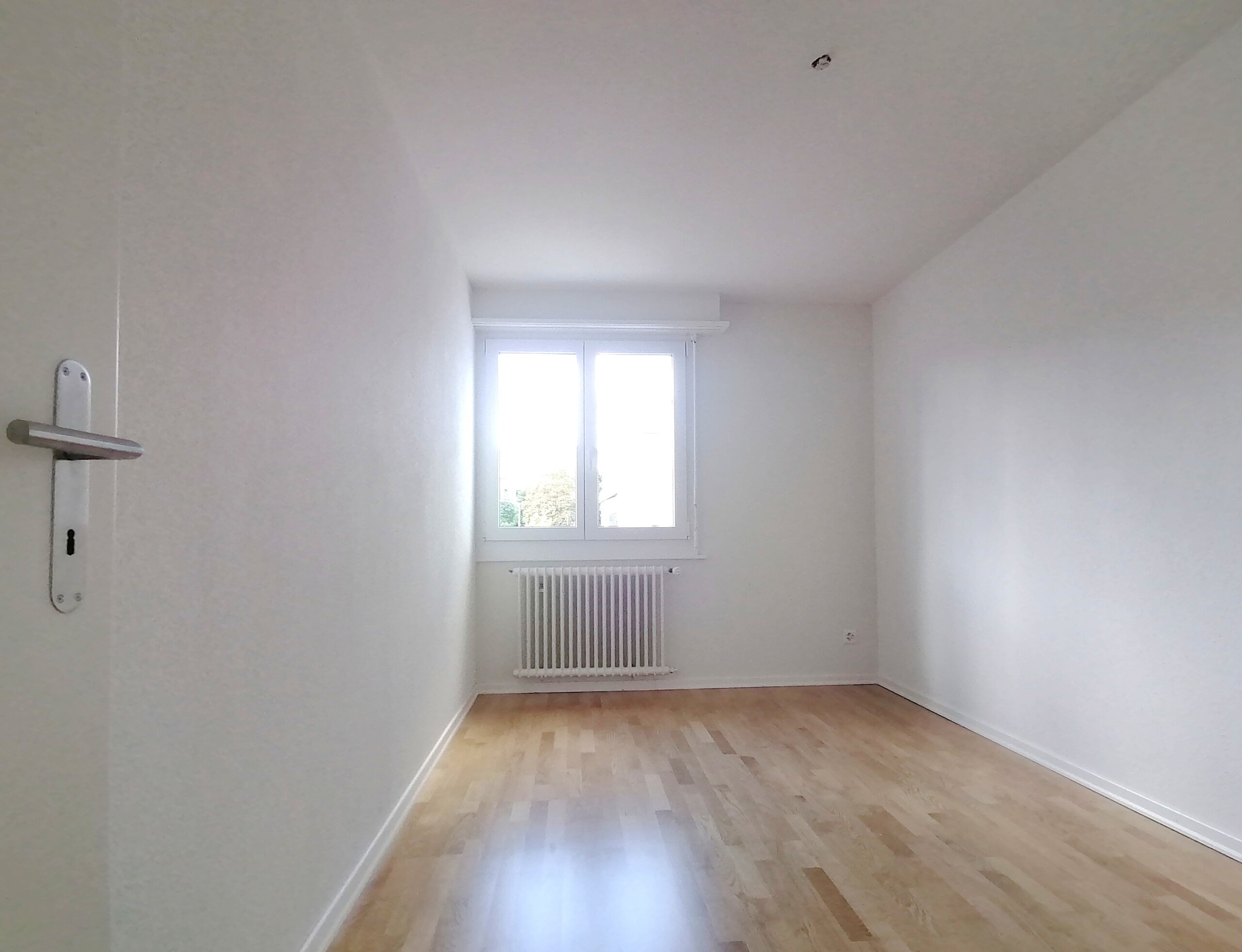 Leerer heller Raum mit Fenster und Heizkörper