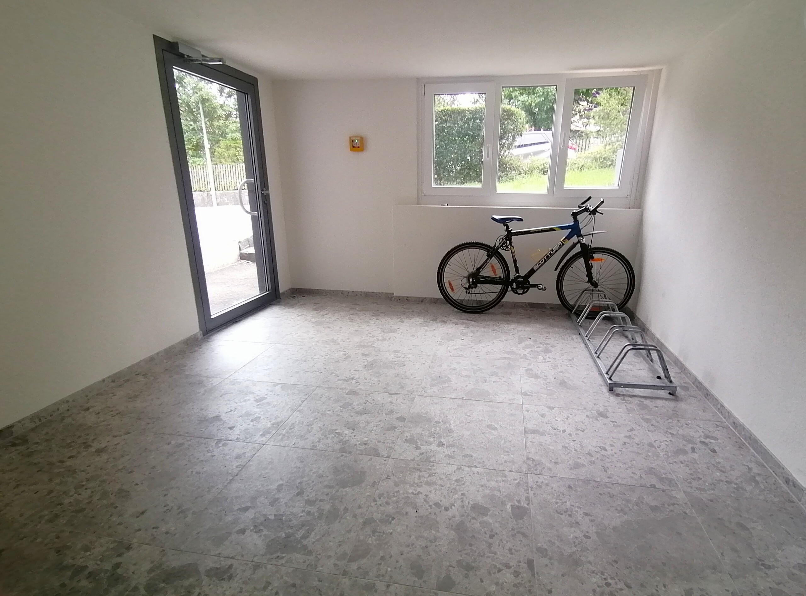 Heller, leerer Innenraum mit Fensterfront und Fahrrad