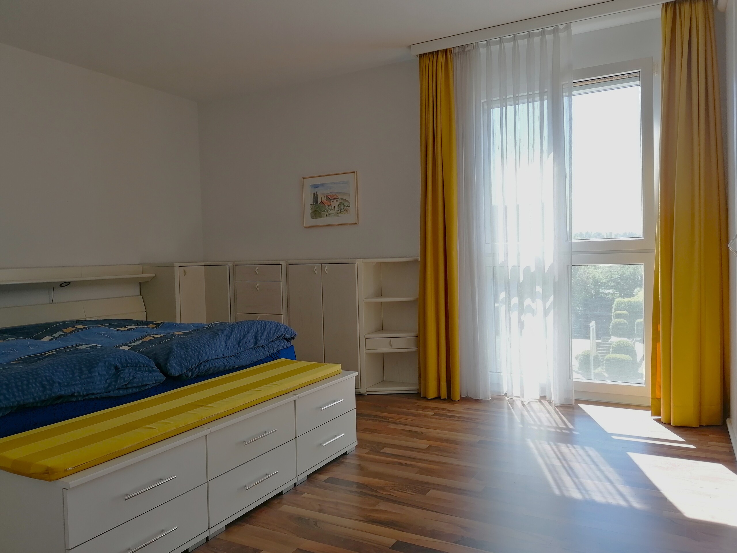 Helles Schlafzimmer mit großem Fenster und integriertem Stauraum