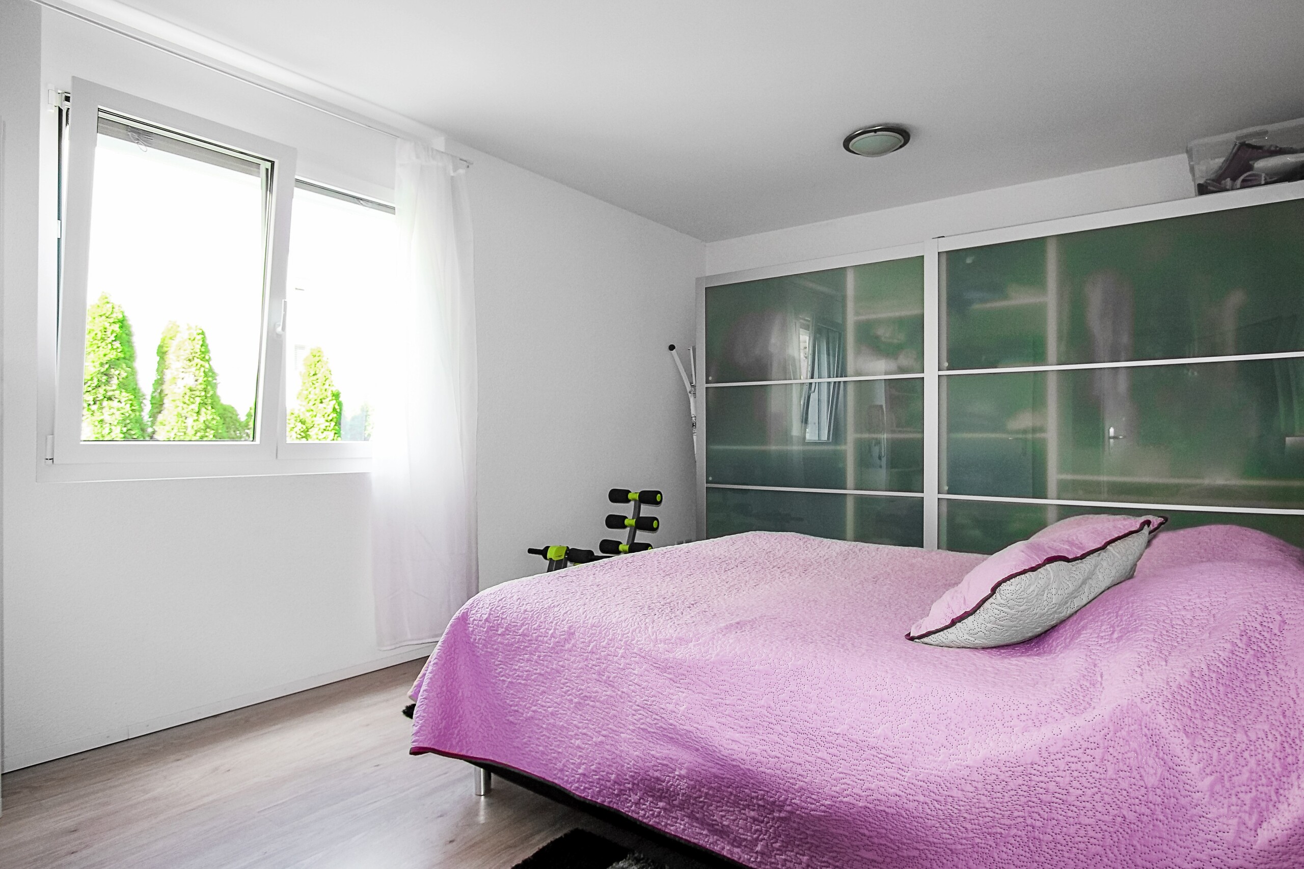 Helles Schlafzimmer mit pinker Bettdecke