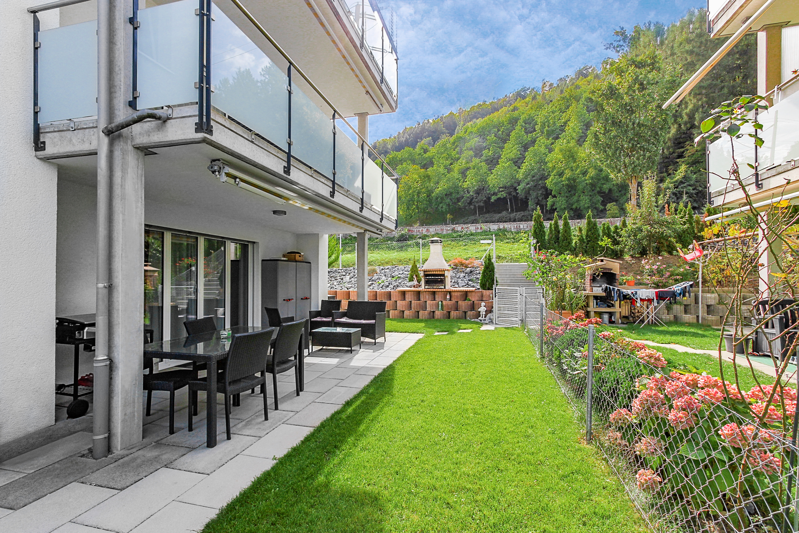 Garten mit Terrasse und Balkon eines modernen Mehrfamilienhauses