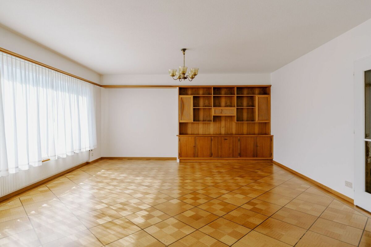 Leeres Wohnzimmer mit Holzboden und Einbauschrank