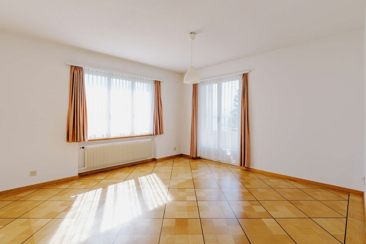 Leerer heller Wohnraum mit Fenstern und Fliesenboden