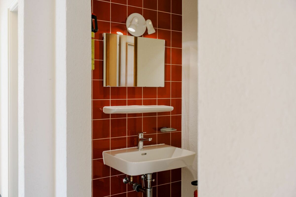 Kleines Gäste-WC mit roter Fliesenrückwand