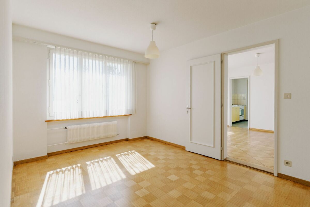 Helles, leeres Zimmer mit Blick in die Küche