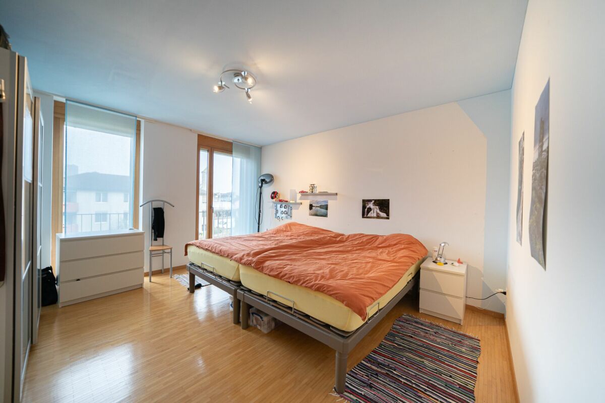 Helles Schlafzimmer mit Doppelbett und Balkonfenstern