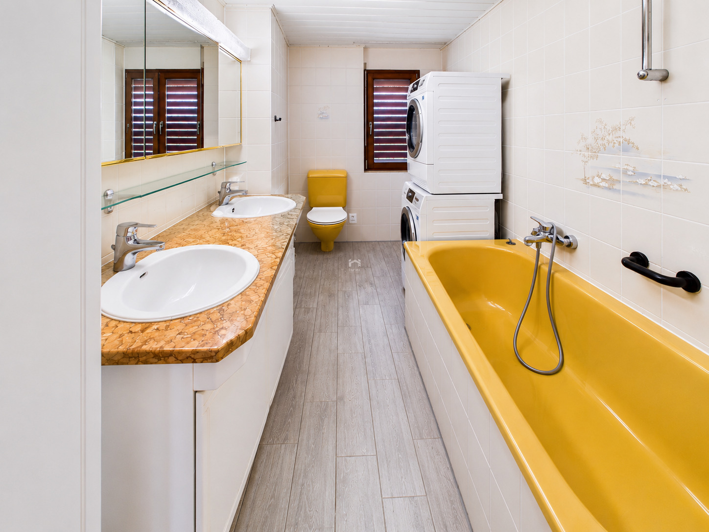 Langer Badezimmerraum mit gelber Badewanne und Waschtisch