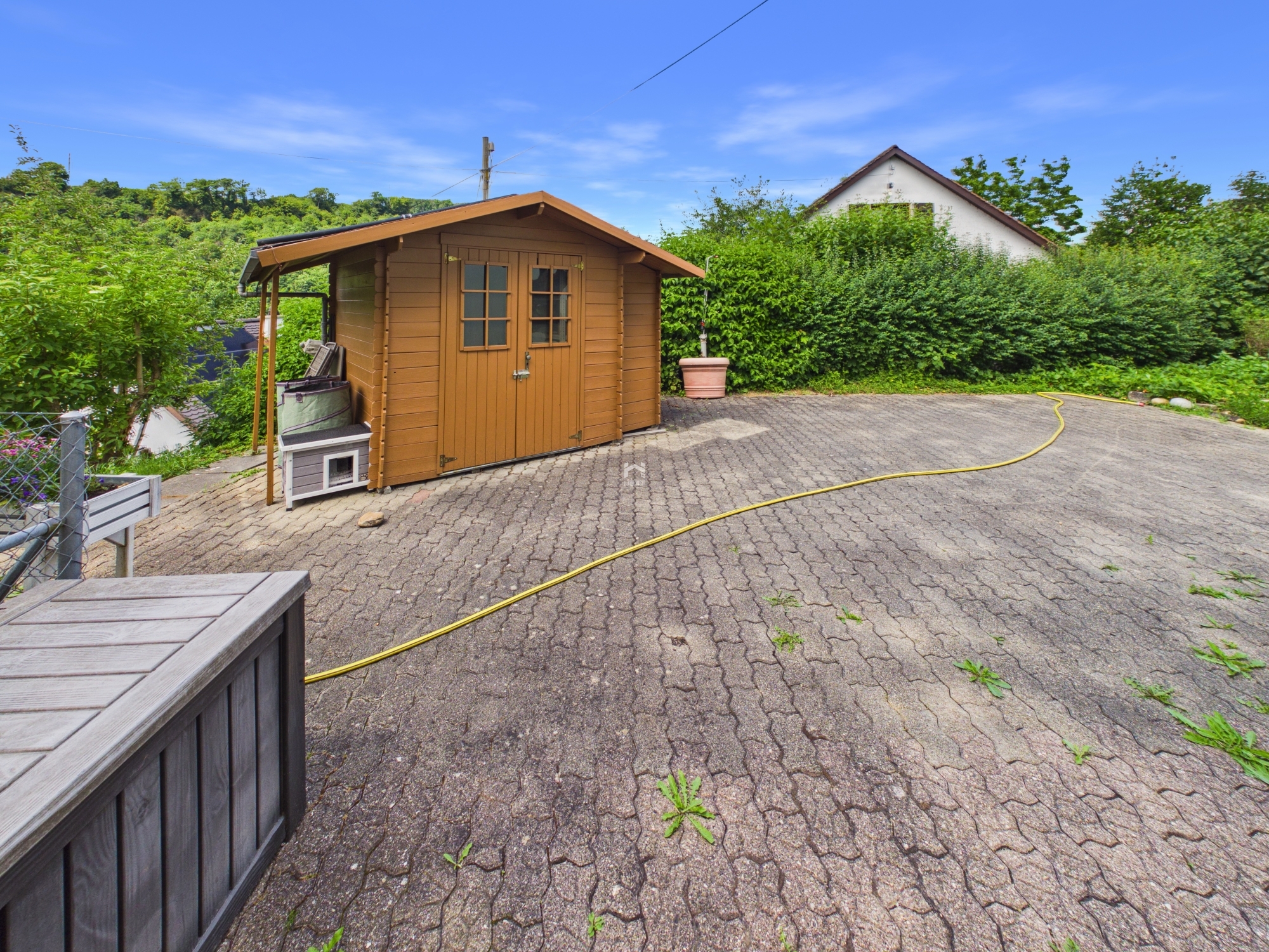 Garten mit Holzschuppen und gepflasterter Fläche