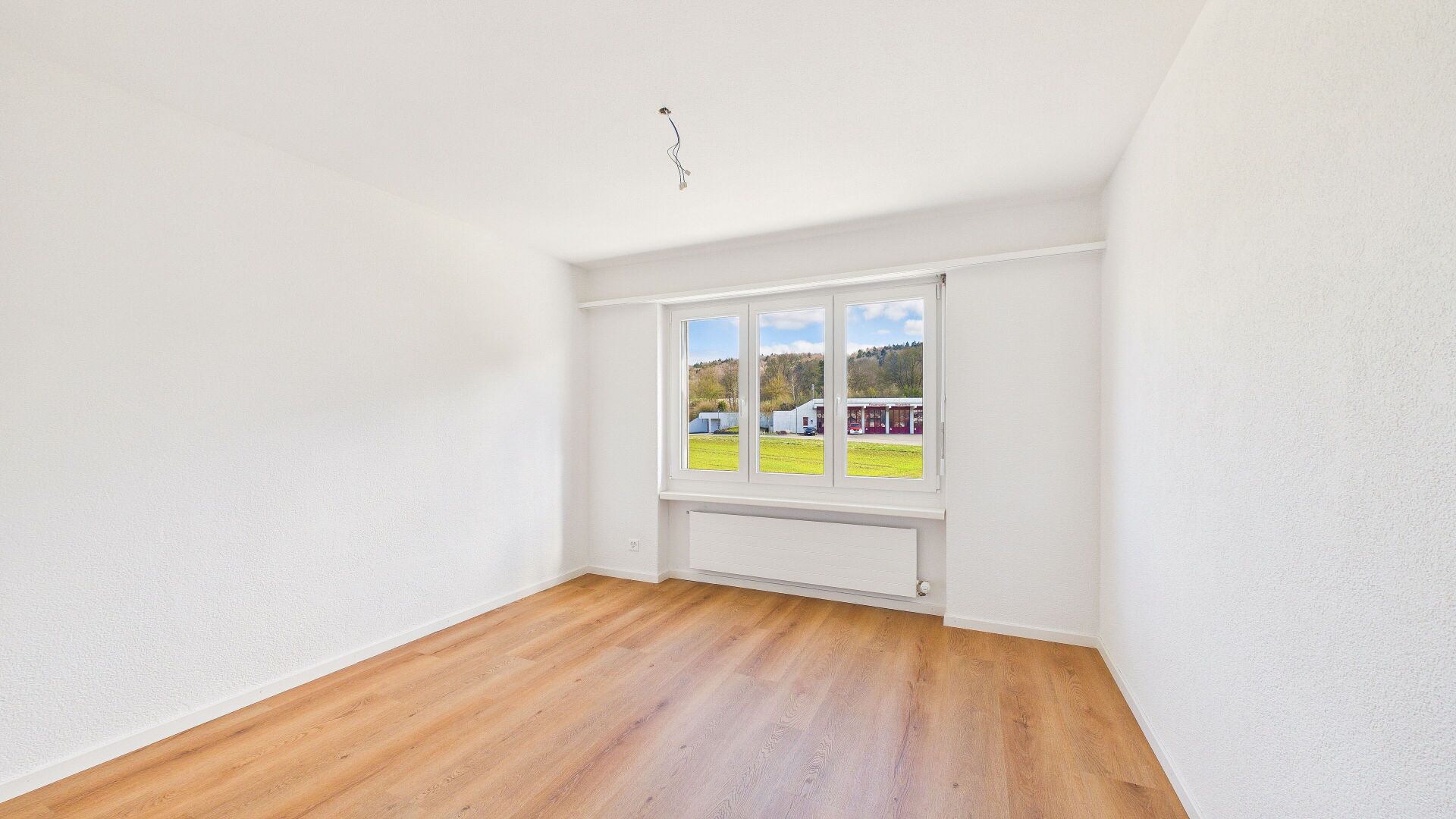 Heller leerer Raum mit Fenster und Holzoptik-Boden