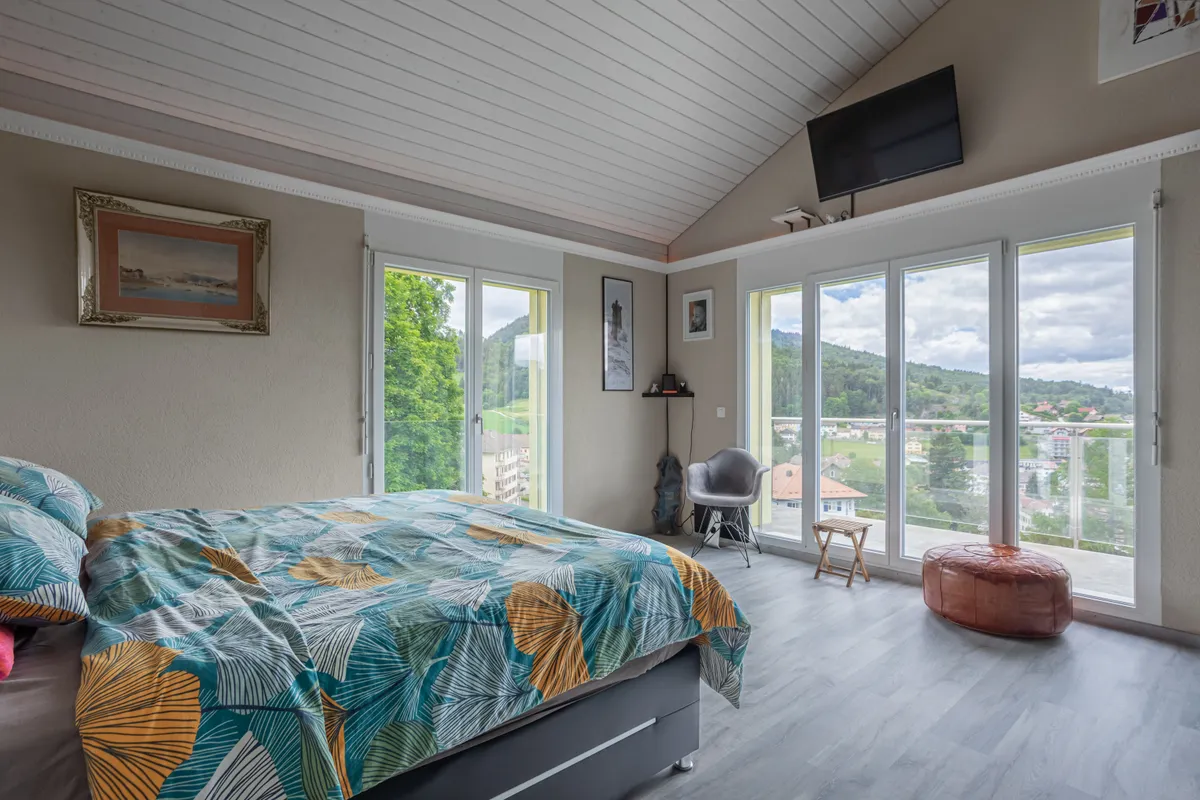 Schlafzimmer mit Panoramafenstern und Balkonblick