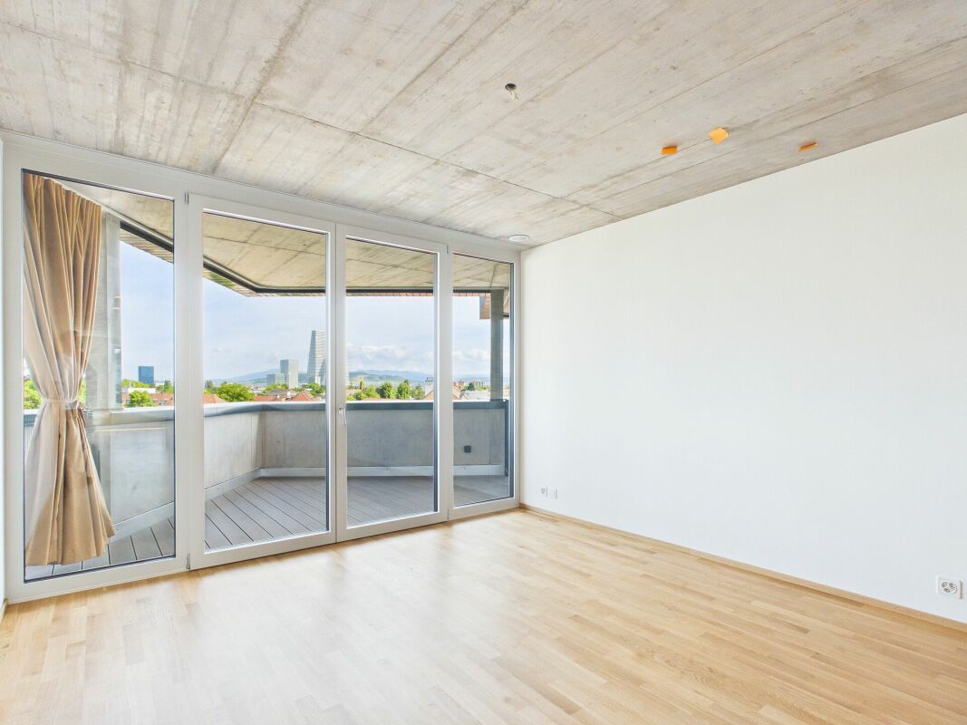 Heller leerer Wohnraum mit Balkon und Stadtblick