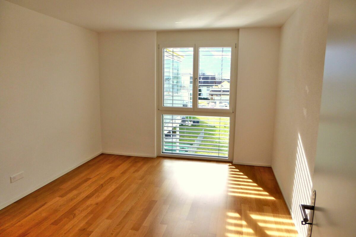 Heller leerer Raum mit Holzfußboden und großem Fenster