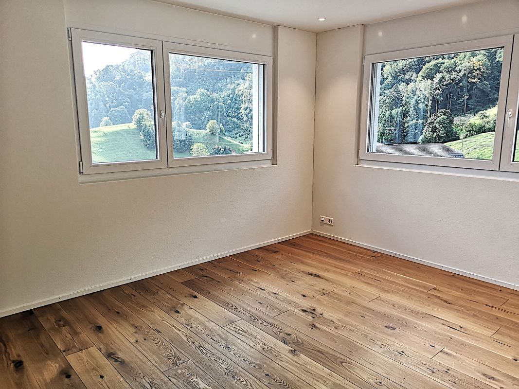 Heller leerer Raum mit Holzboden und zwei Fenstern