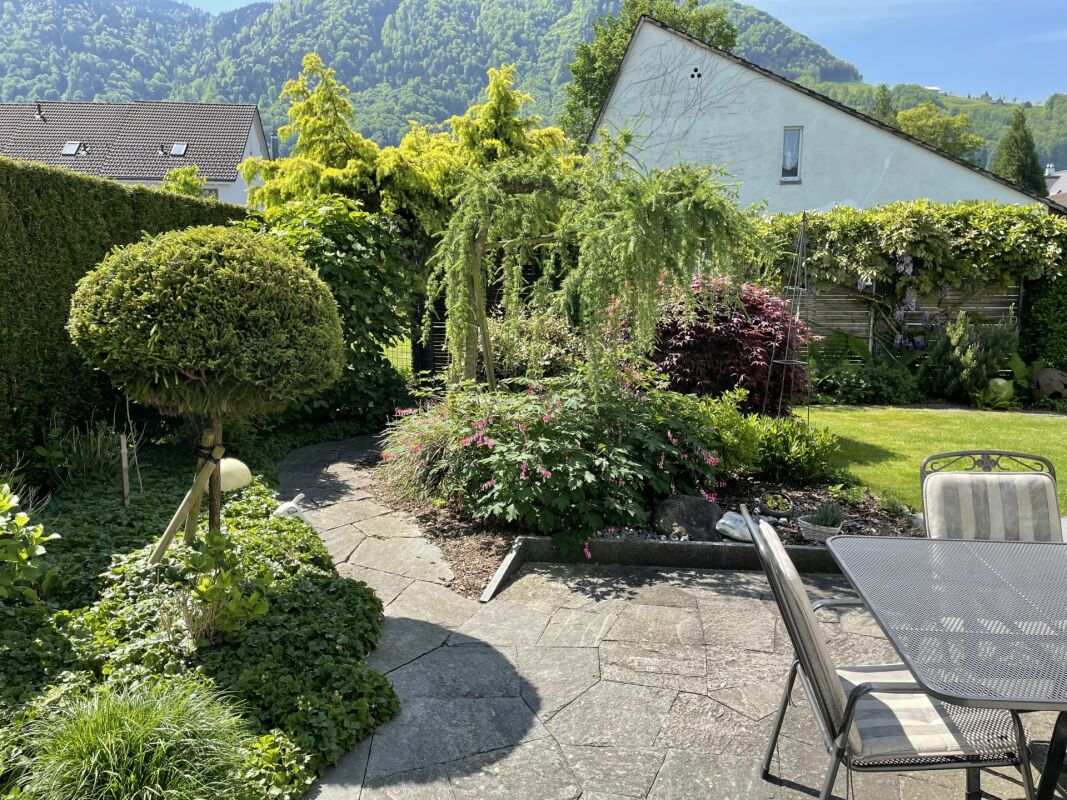 Gepflegter Garten mit Terrasse und Bergkulisse