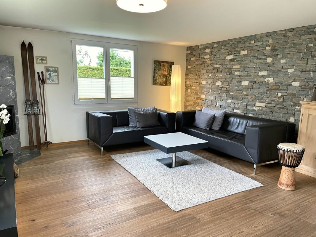 Modernes Wohnzimmer mit Steinwand und schwarzer Ledersitzgruppe