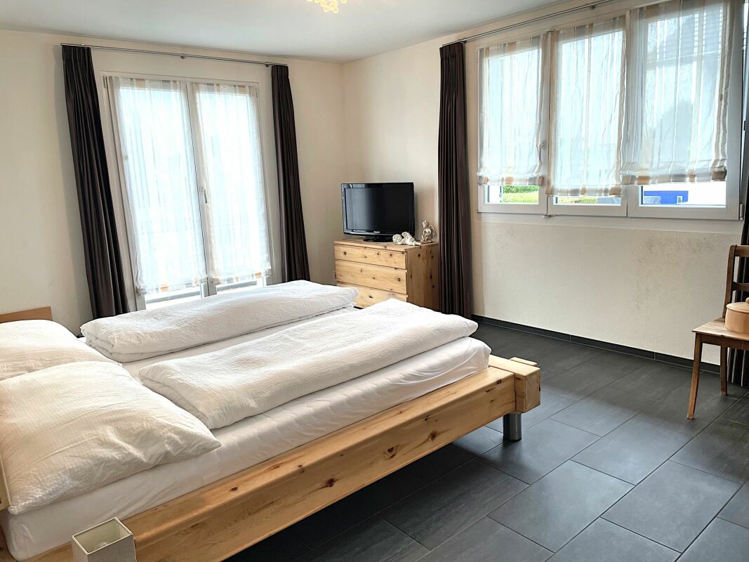 Helles Schlafzimmer mit Holzbett und großen Fenstern