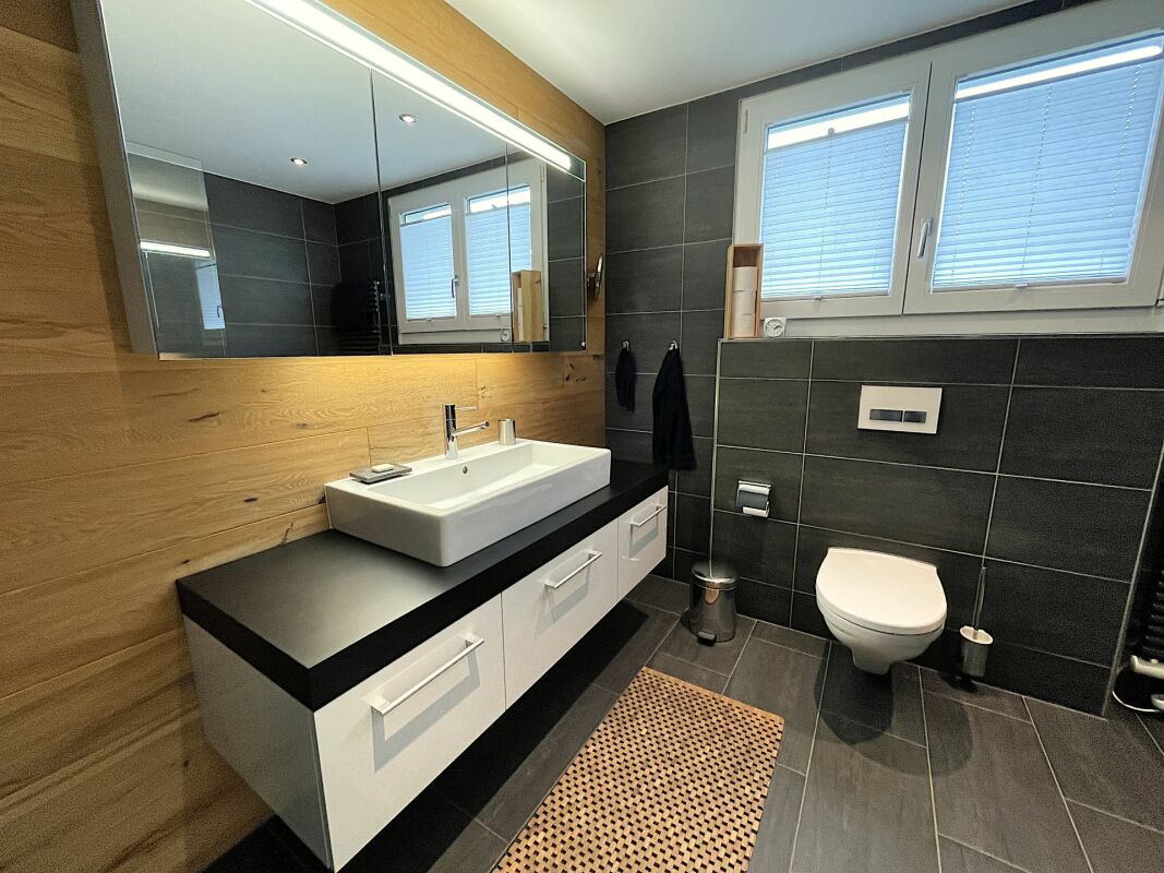 Modernes Badezimmer mit Holzverkleidung und dunklen Fliesen