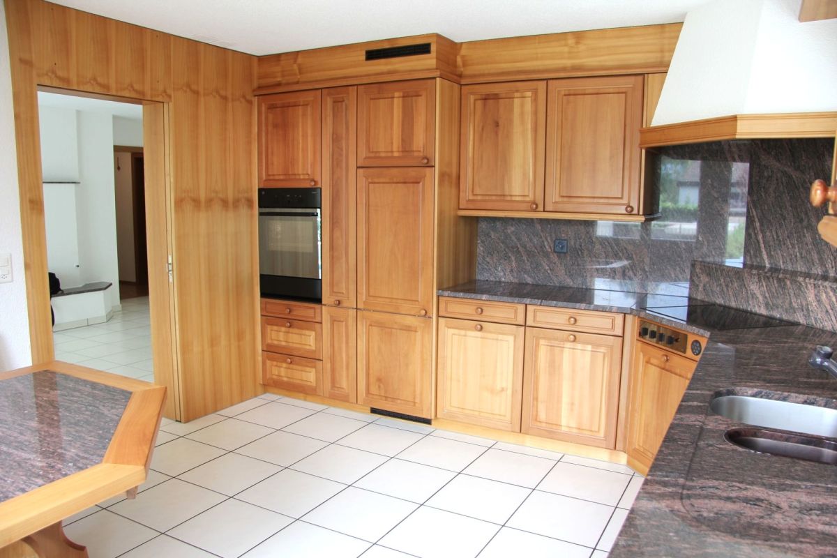 Küche mit Holzfronten und dunkler Stein-Arbeitsplatte