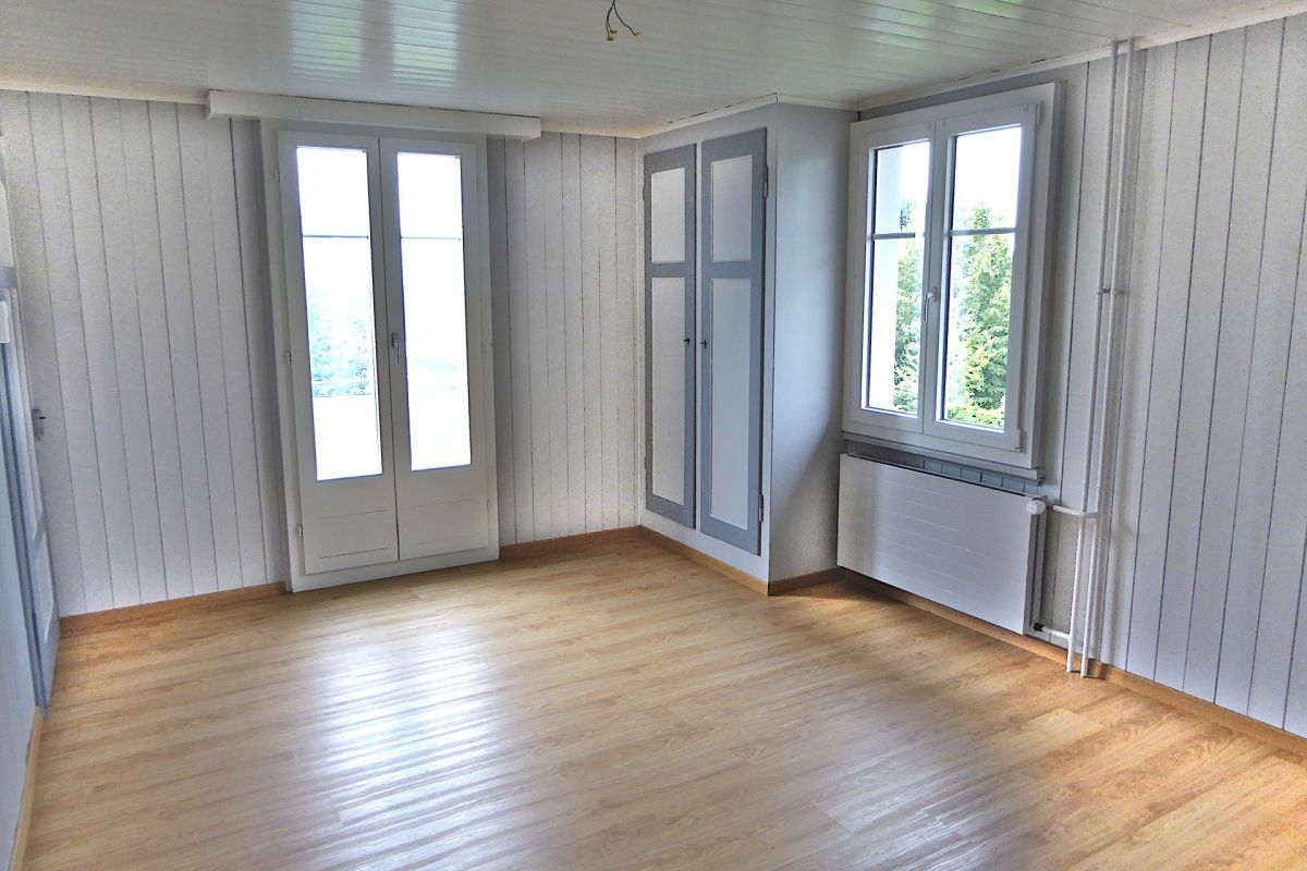 Heller leerer Raum mit Holzboden und mehreren Fenstern