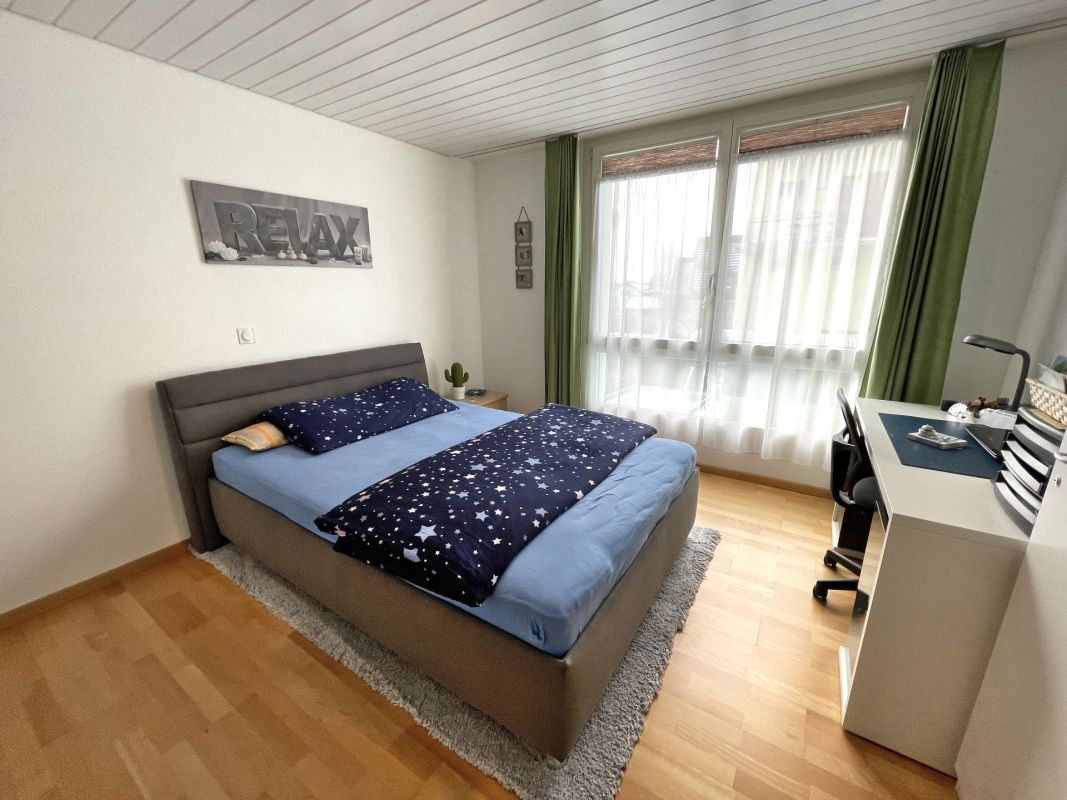 Helles Schlafzimmer mit Doppelbett und Schreibtisch