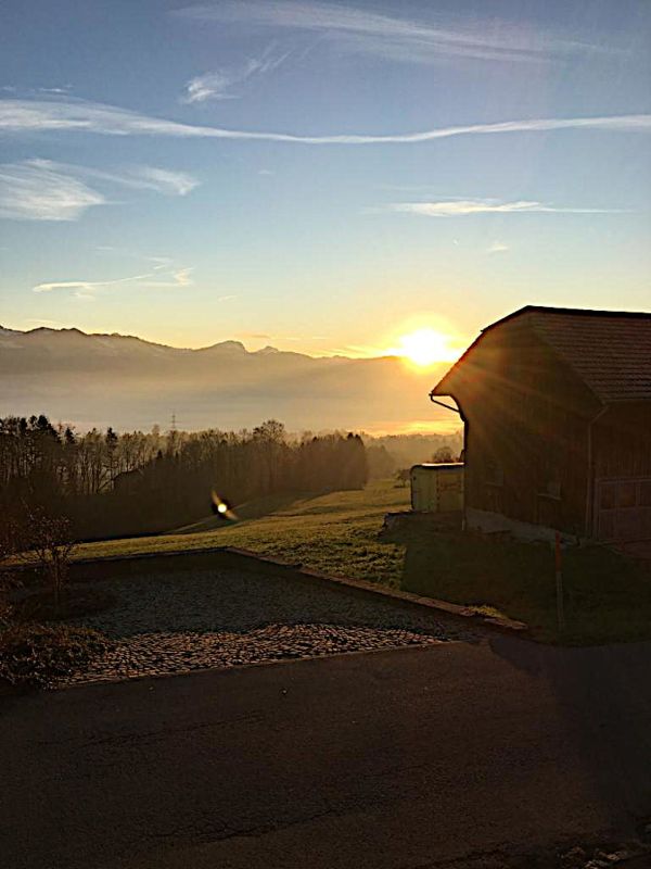 Sonnenaufgang über Landschaft mit Scheunenbau