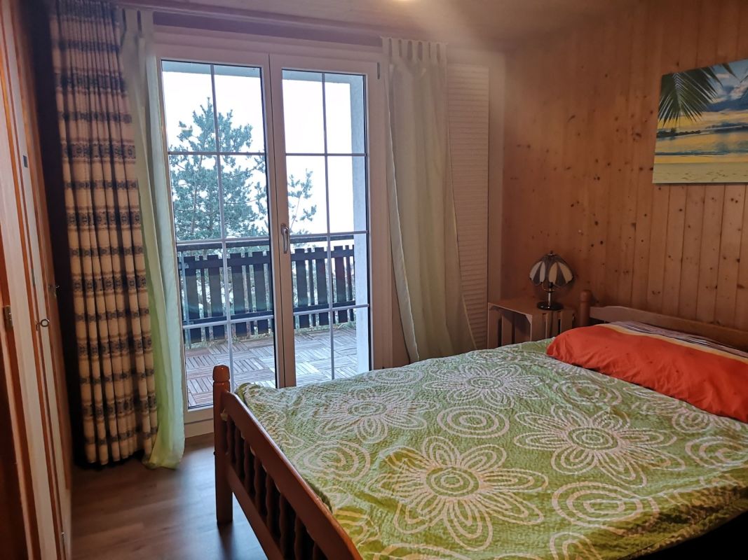 Gemütliches Schlafzimmer mit Holzverkleidung und Balkonblick
