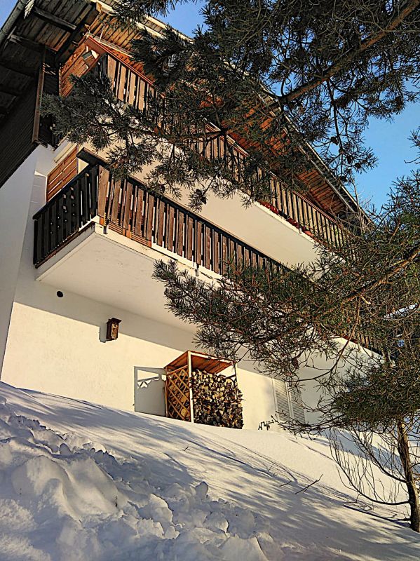 Schneebedecktes Wohnhaus mit Holzbalkonen