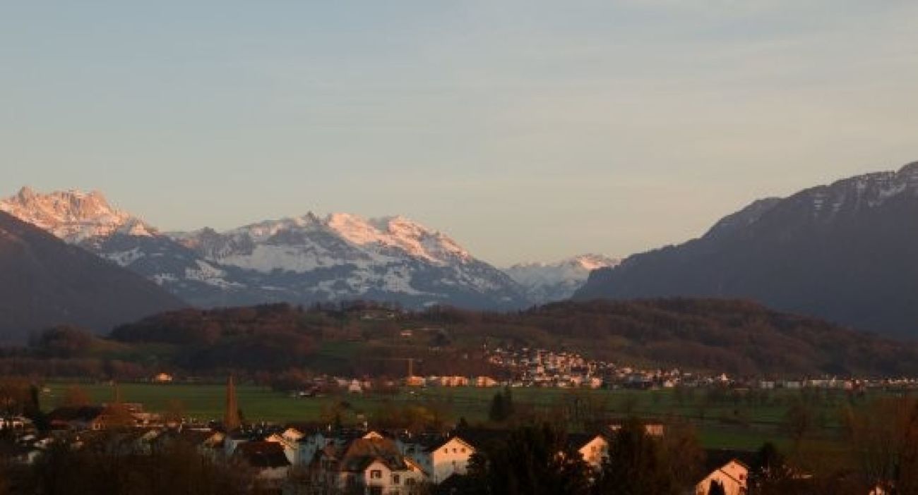 Berglandschaft mit Tal und Ortschaft bei Sonnenuntergang