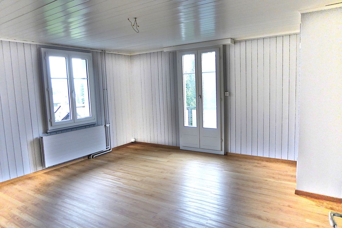 Heller leerer Wohnraum mit Holzboden und weißer Vertäfelung